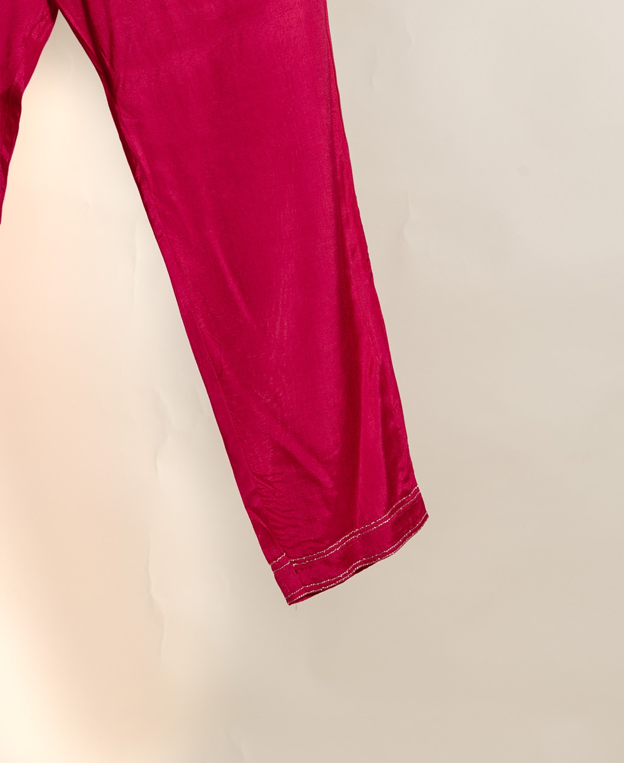 Vibrant magenta silk pants, partial view, with delicate silver double-stitched hem.