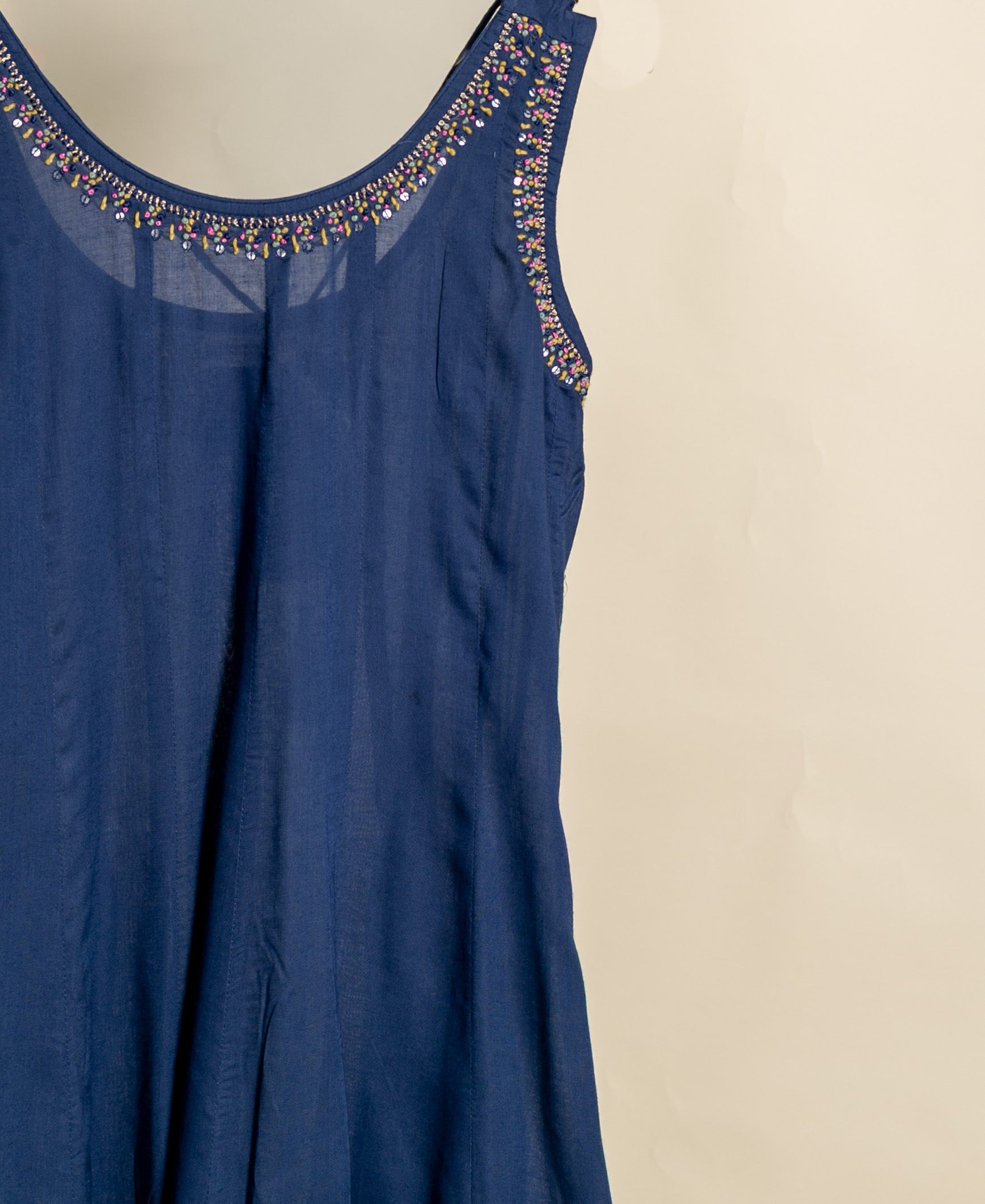 Angled front of indigo sleeveless kurta, intricate multicolored beadwork on neckline and armholes.