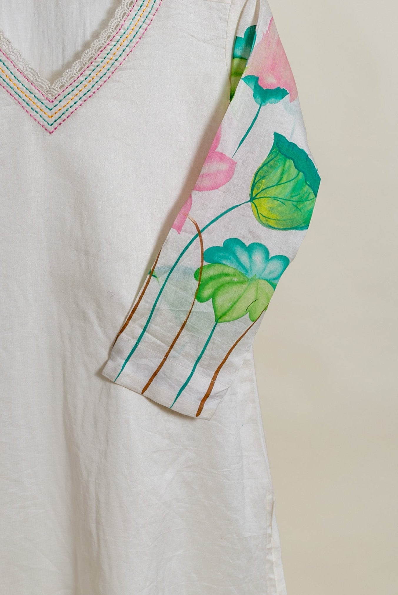 A close-up of a white, hand-painted lotus print kurta with lace trim.