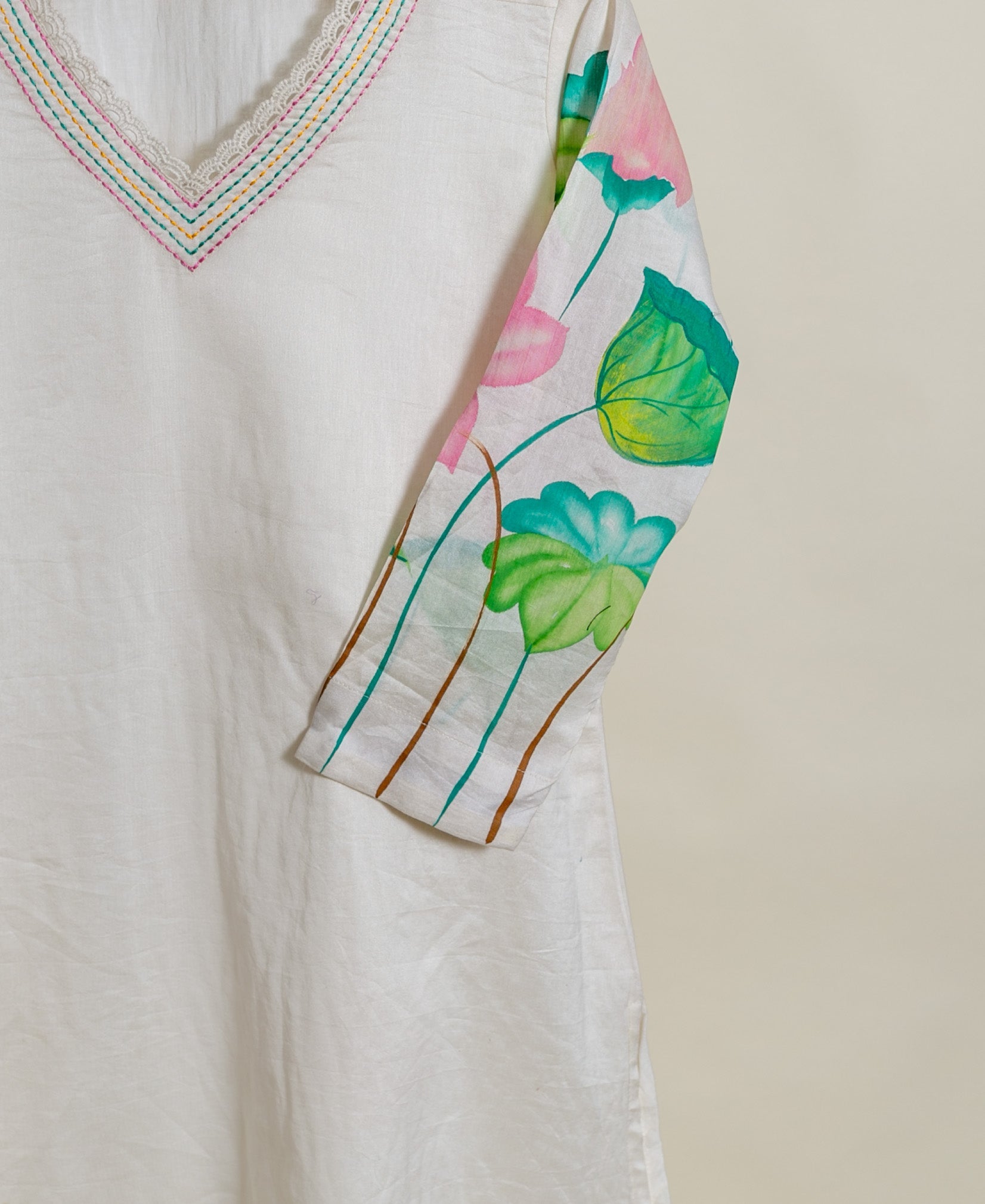 A close-up of a white, hand-painted lotus print kurta with lace trim.