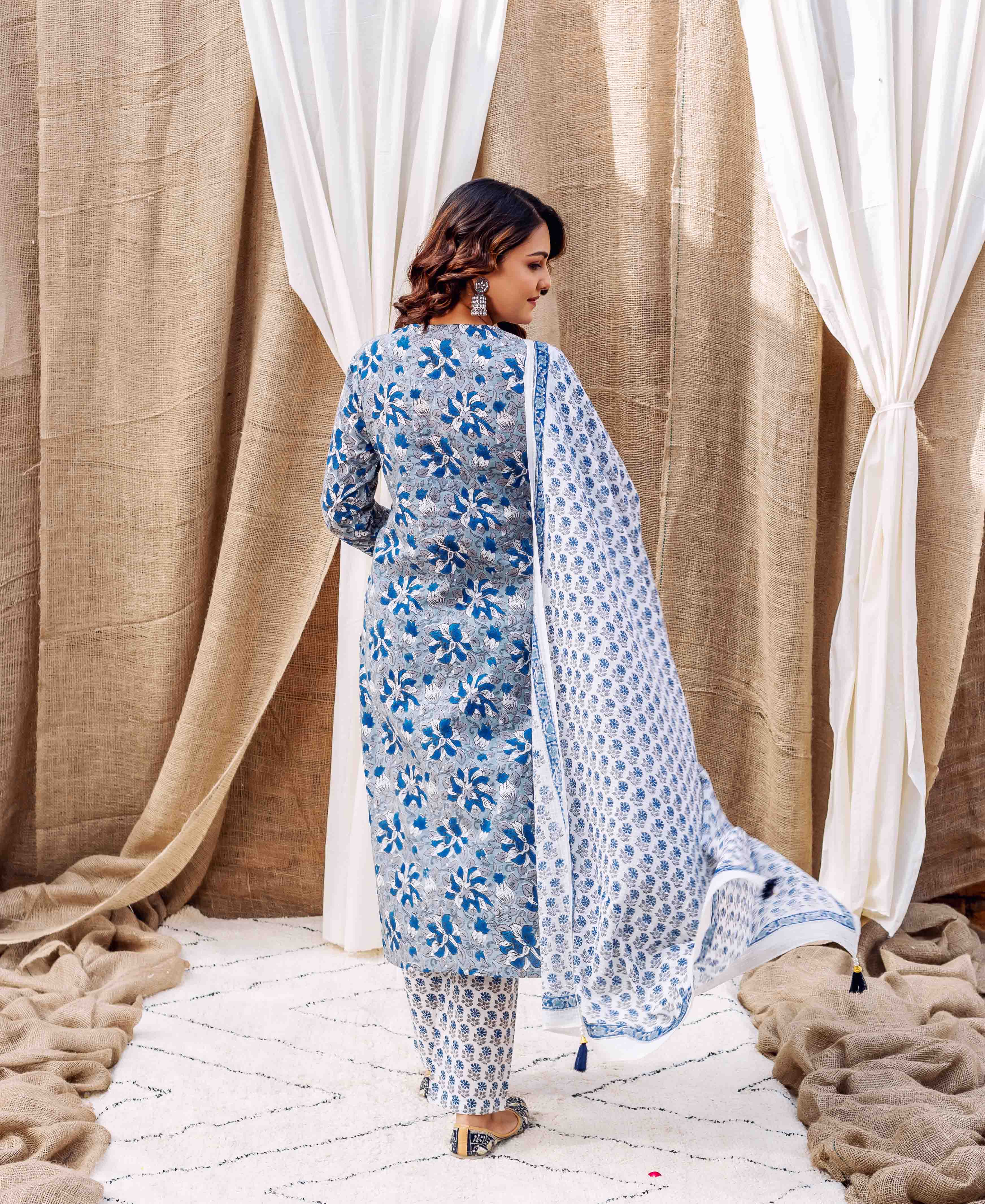 Model's back view in grey and blue hand-block-printed floral kurta set with dupatta.