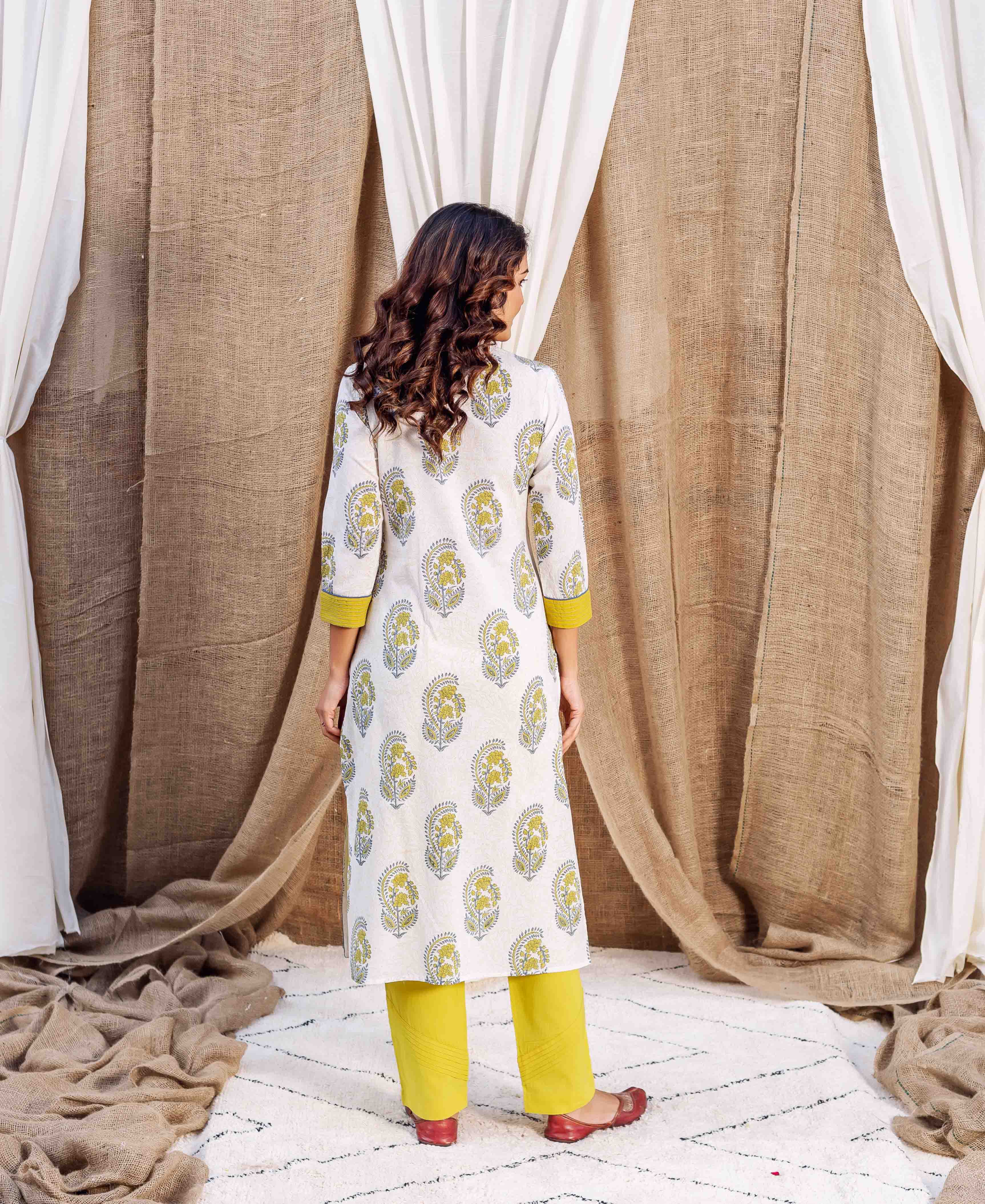 Rear view of woman in white block-printed straight kurta with yellow-grey design, lime green pants.