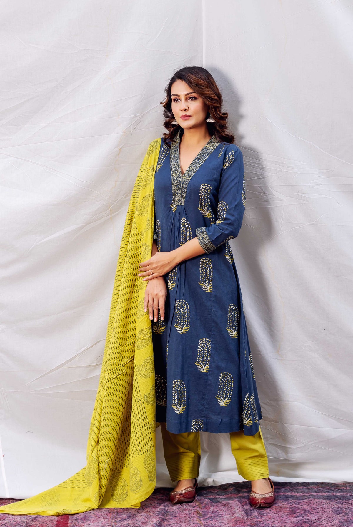 A model wearing an indigo and ochre block-printed A-line kurta with a yellow dupatta.