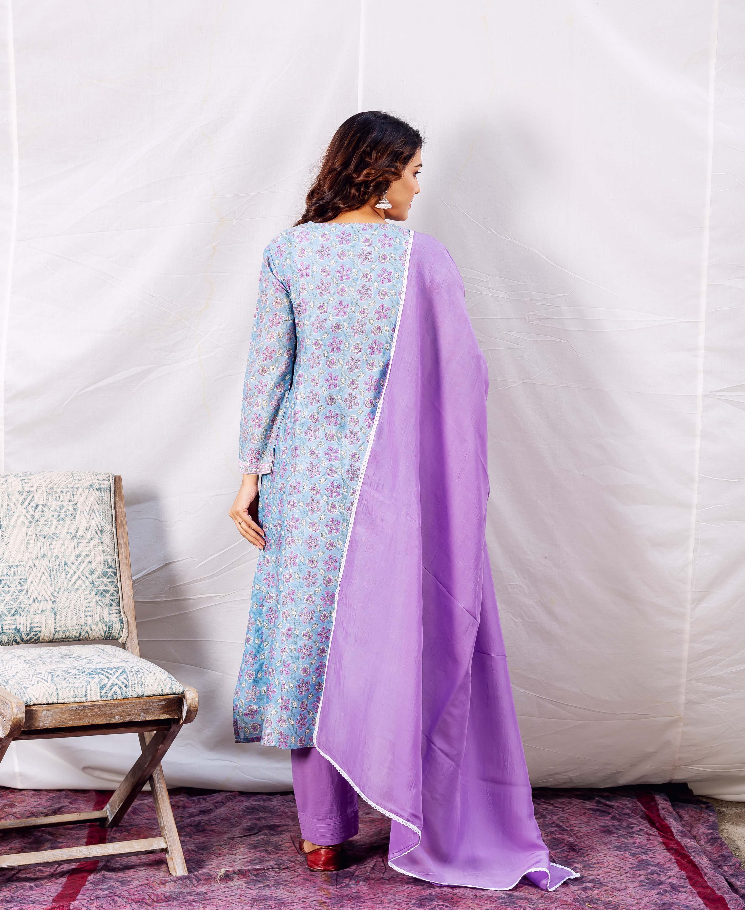Model back view wearing blue floral hand-block printed kurta with purple dupatta and pants.