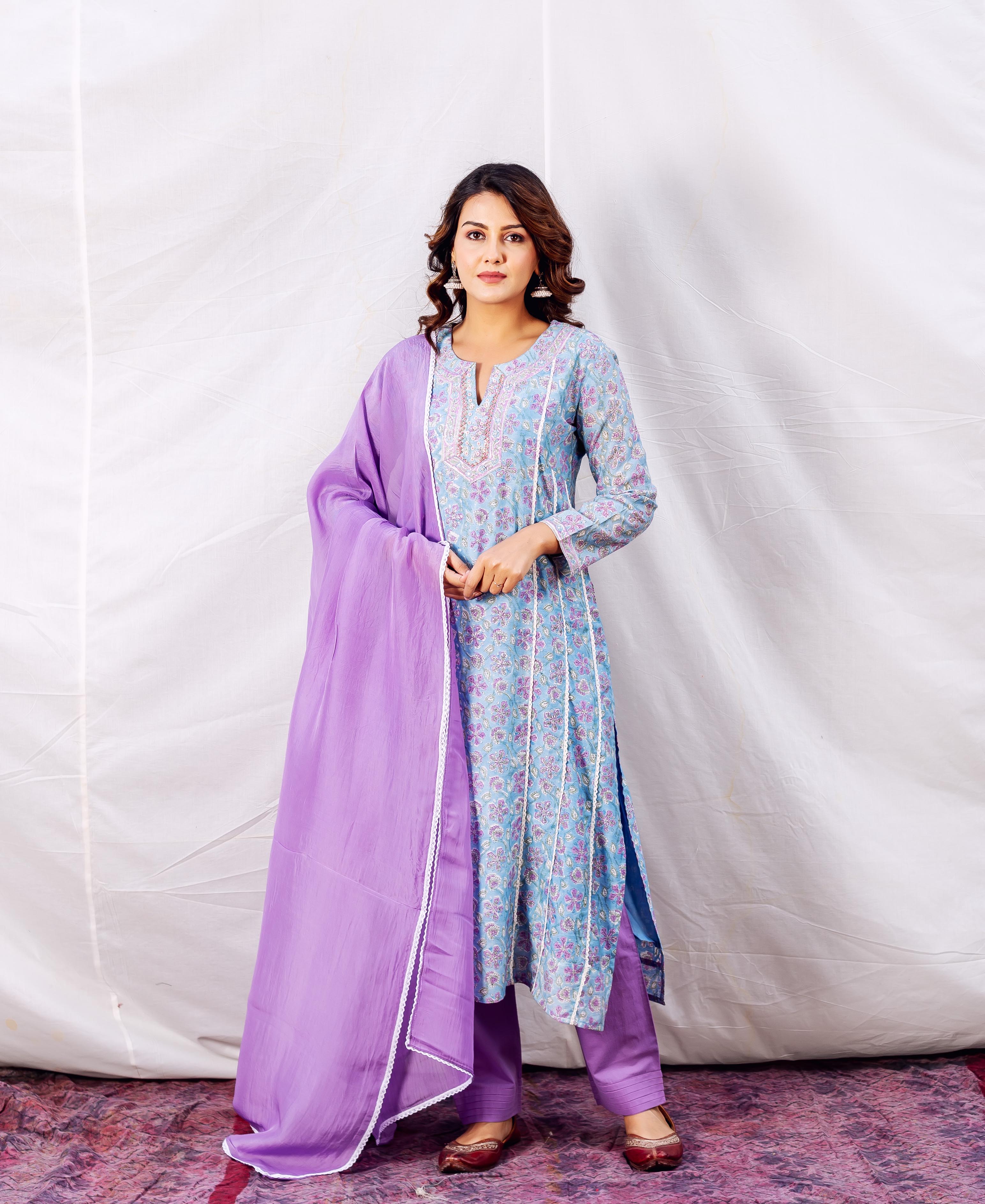 A woman models a light blue floral print kurta with purple accents and a matching dupatta.