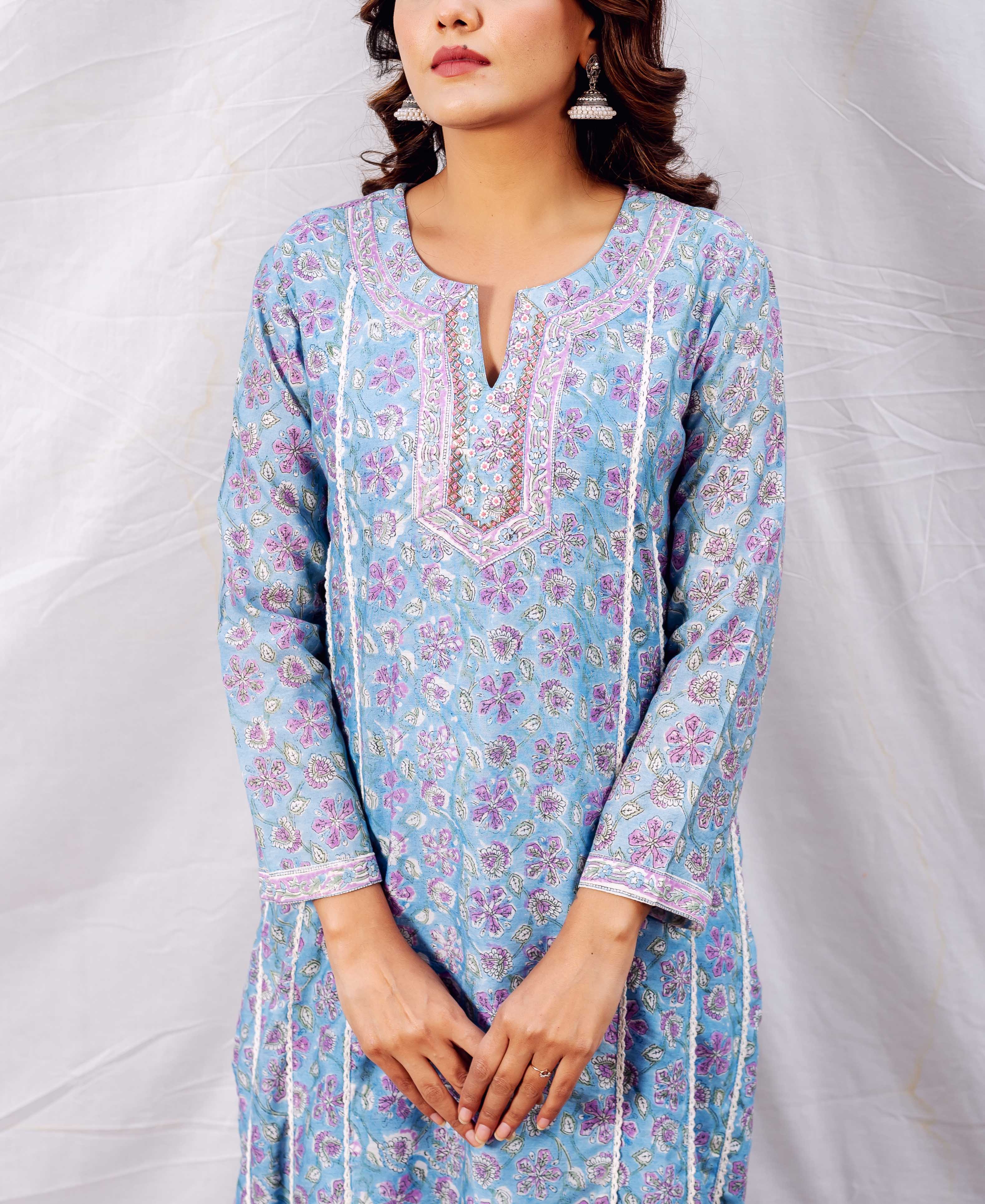 Model in light blue floral hand-block printed kurta with purple patterns and embroidered neckline.