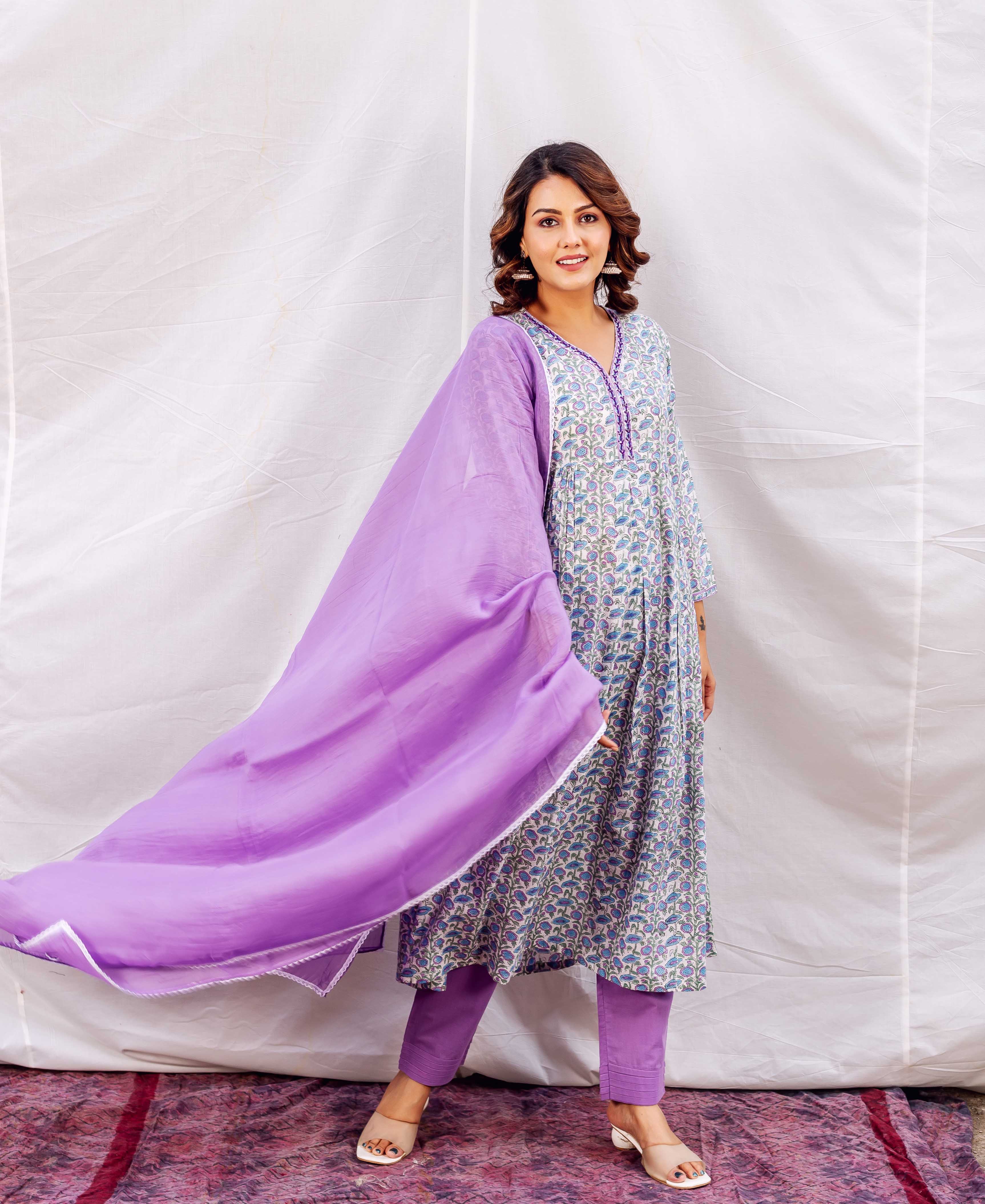 Smiling model in purple and blue hand-block printed A-line kurta set with flowing dupatta.