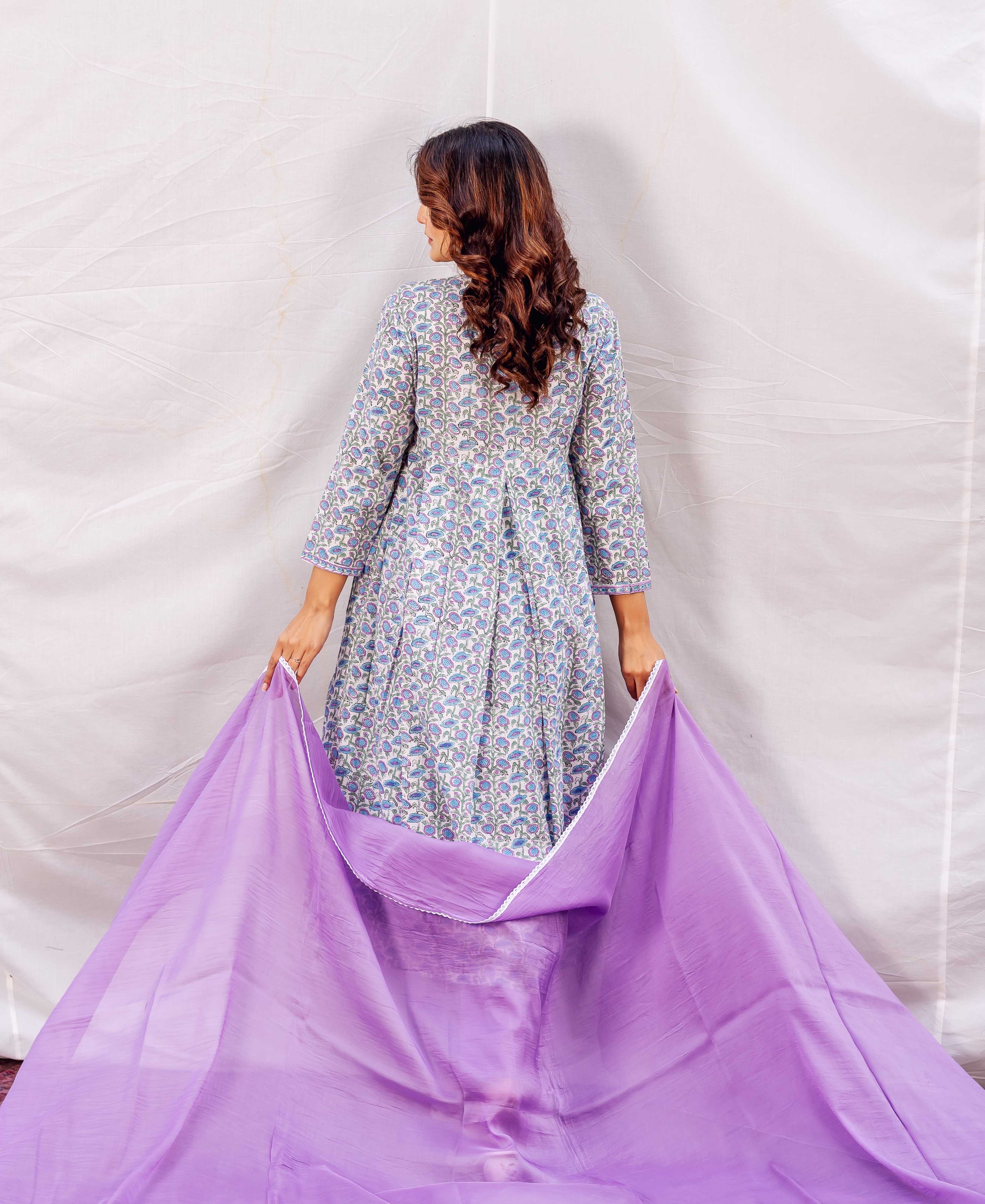 Rear view of woman in blue floral block-printed A-line kurta holding a wide purple dupatta.
