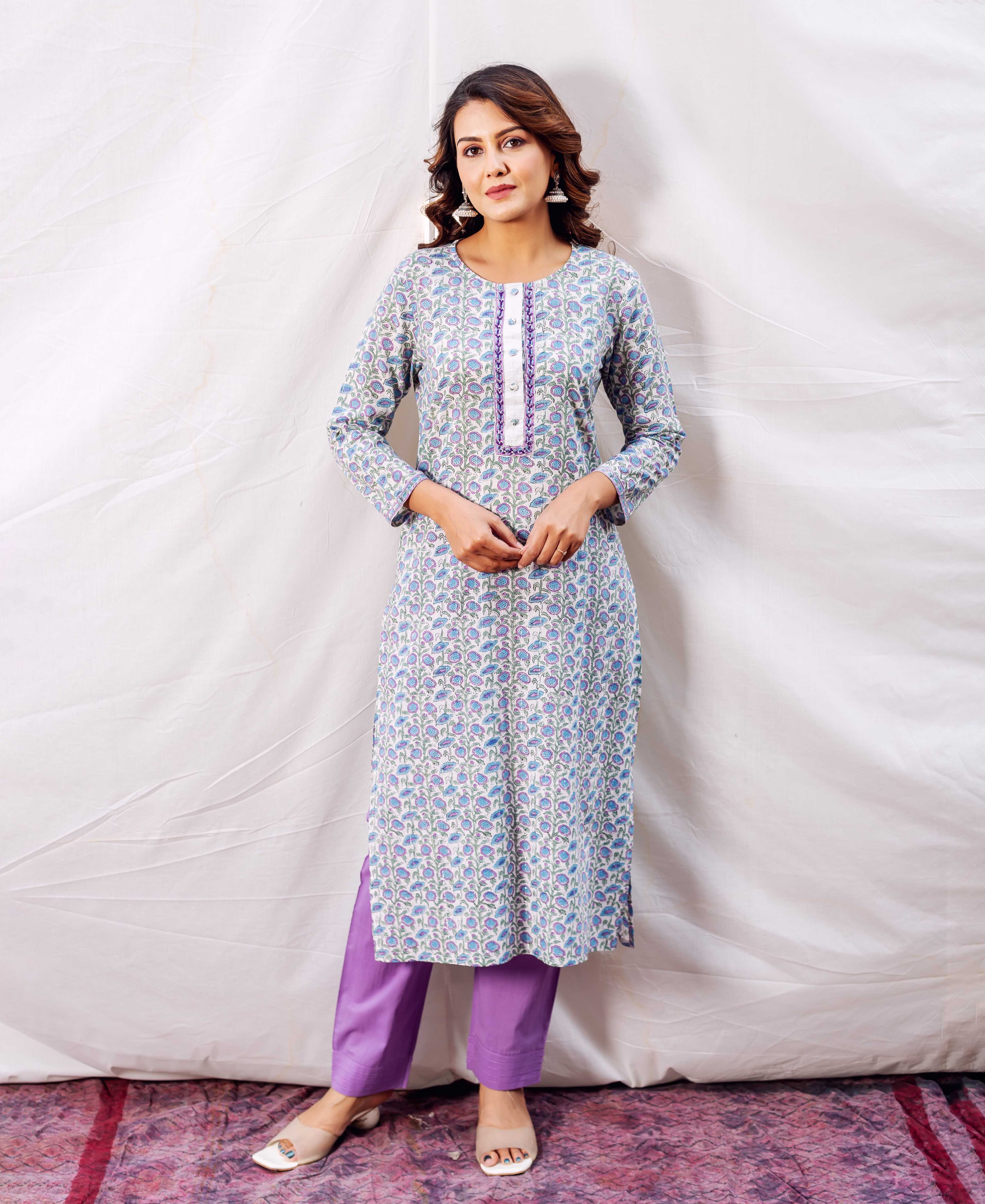 Woman in a white hand-block-printed blue floral kurta with purple trim and matching straight pants.