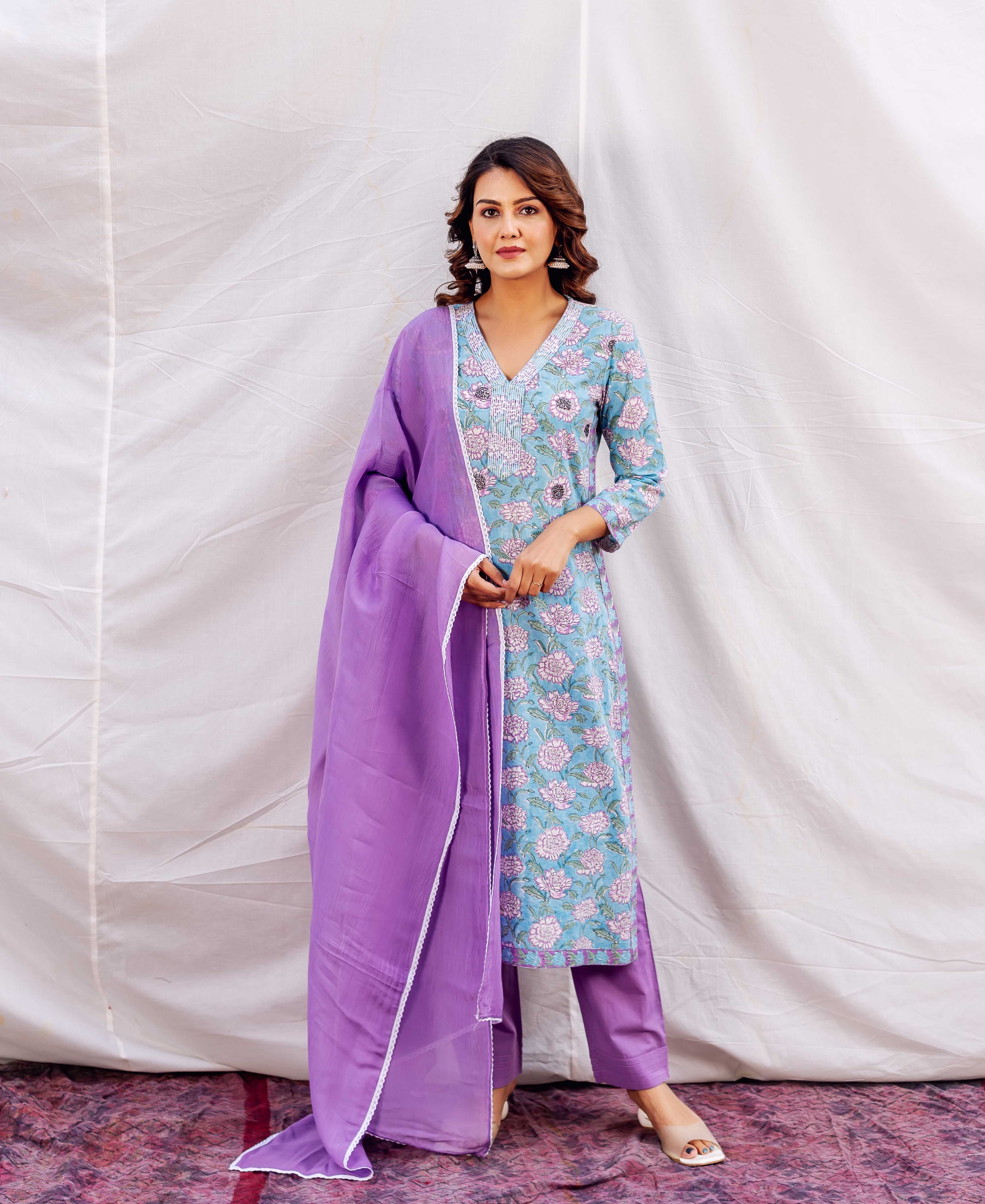 Model wears light blue straight kurta with purple floral print, embroidered neckline, and purple dupatta.