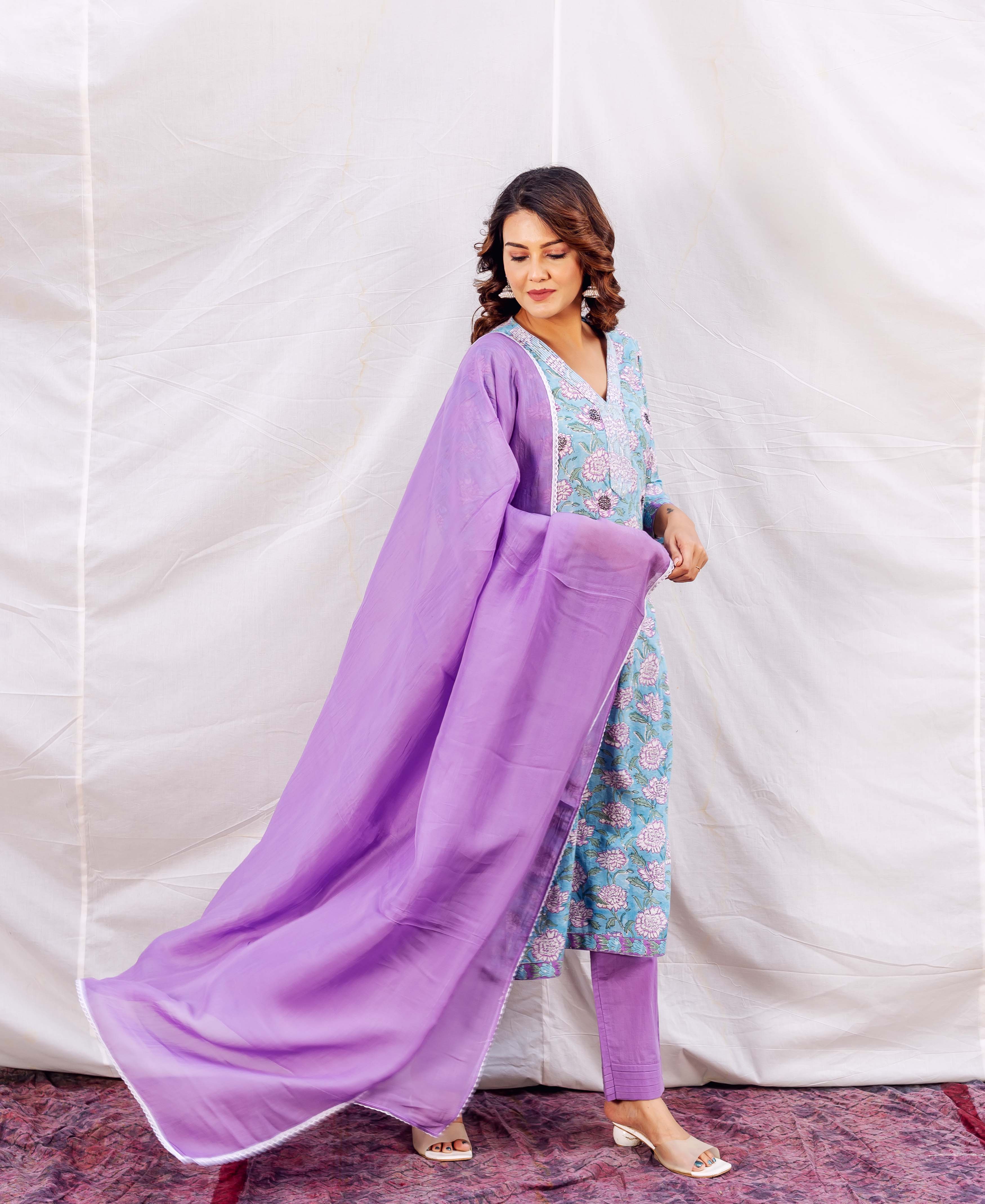 Model wears light blue hand-block printed floral kurta set with a flowing lavender dupatta.