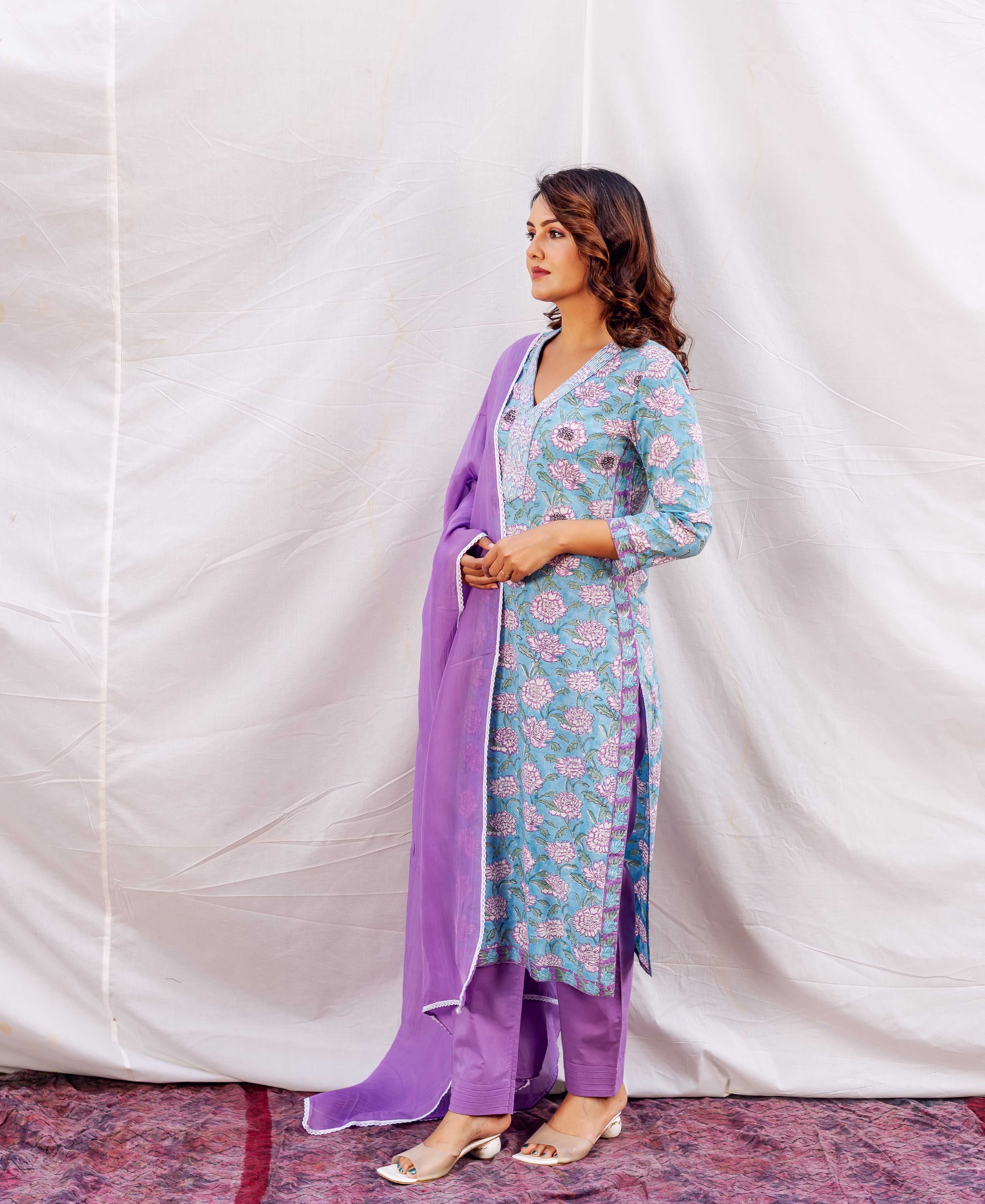 Woman in light blue floral hand-block printed kurta, purple pants, and matching dupatta.