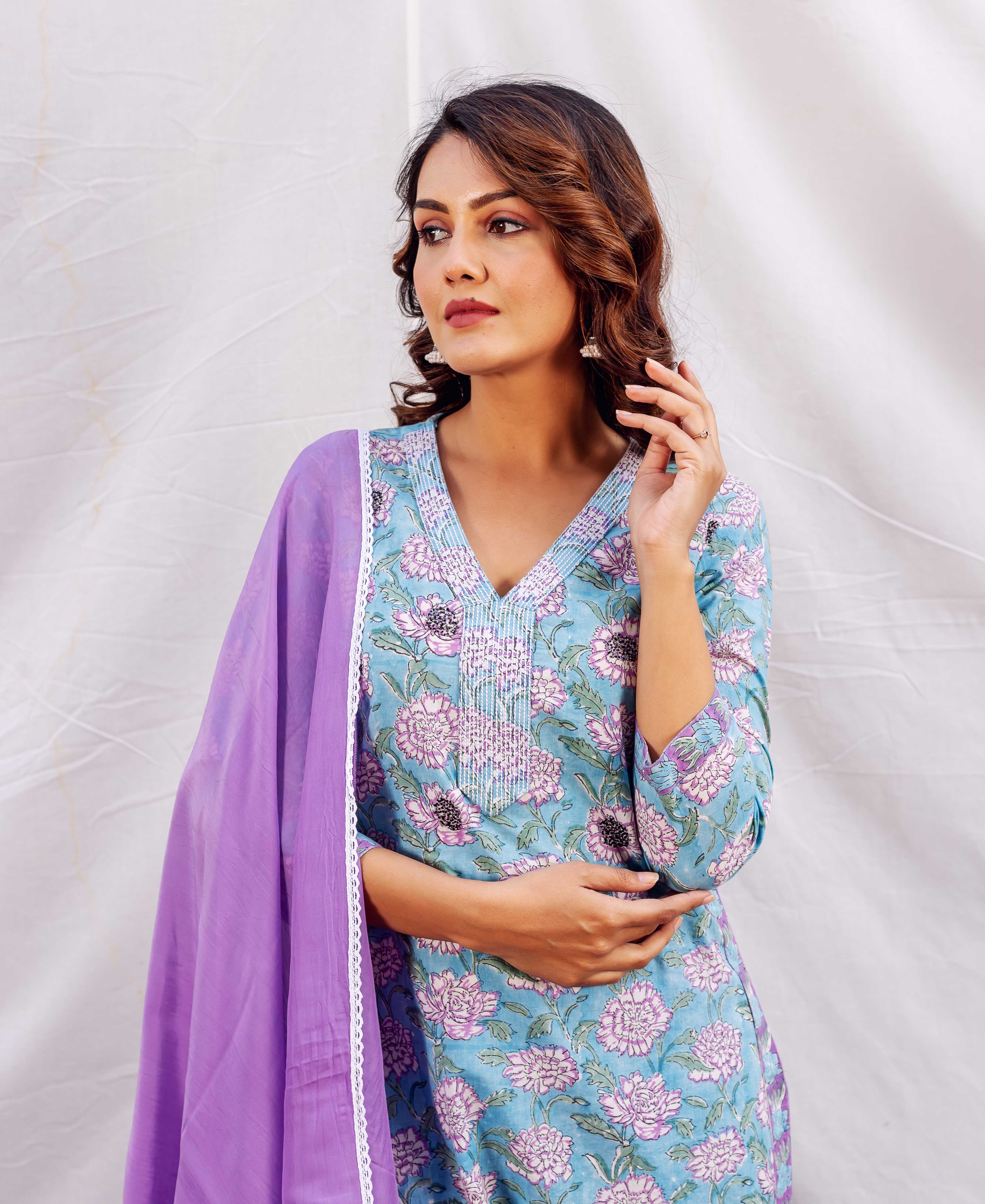 Three-quarter view of model in light blue floral embroidered kurta with purple dupatta.