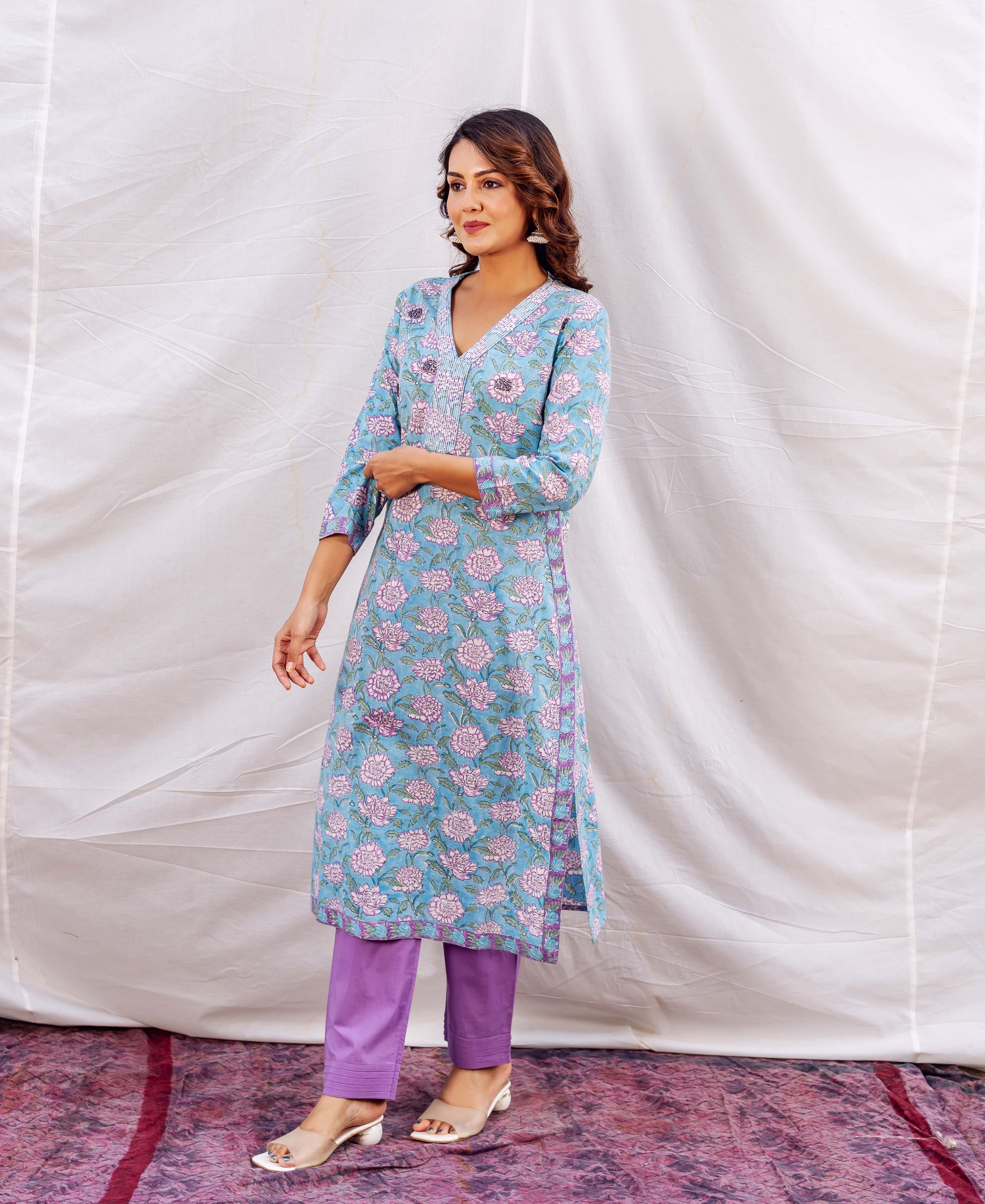 Model wears missprint blue floral hand-block-printed kurta with white embroidery and purple pants.