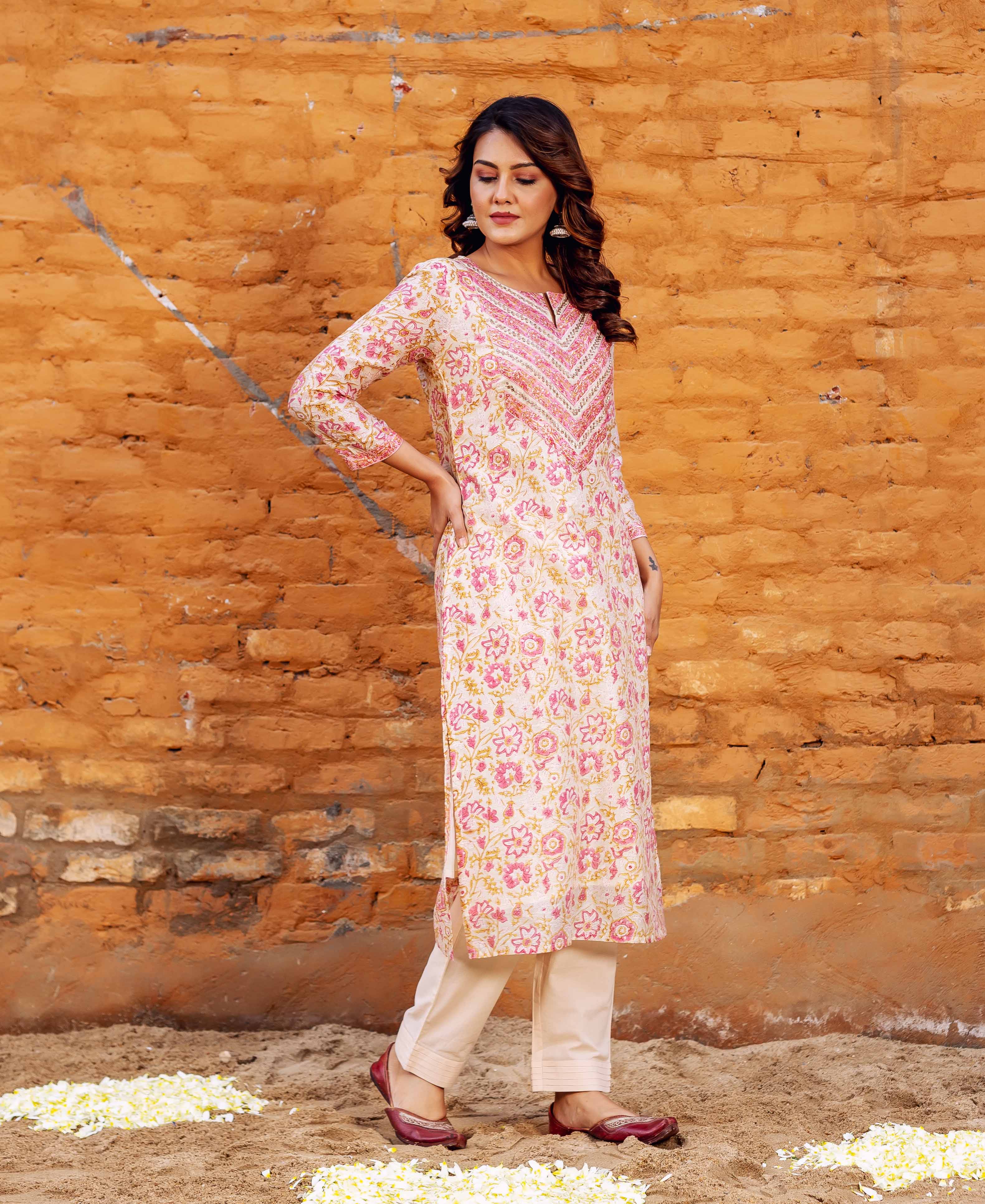 Side view model wearing cream pink golden block print kurta with embroidered yoke, beige pants.
