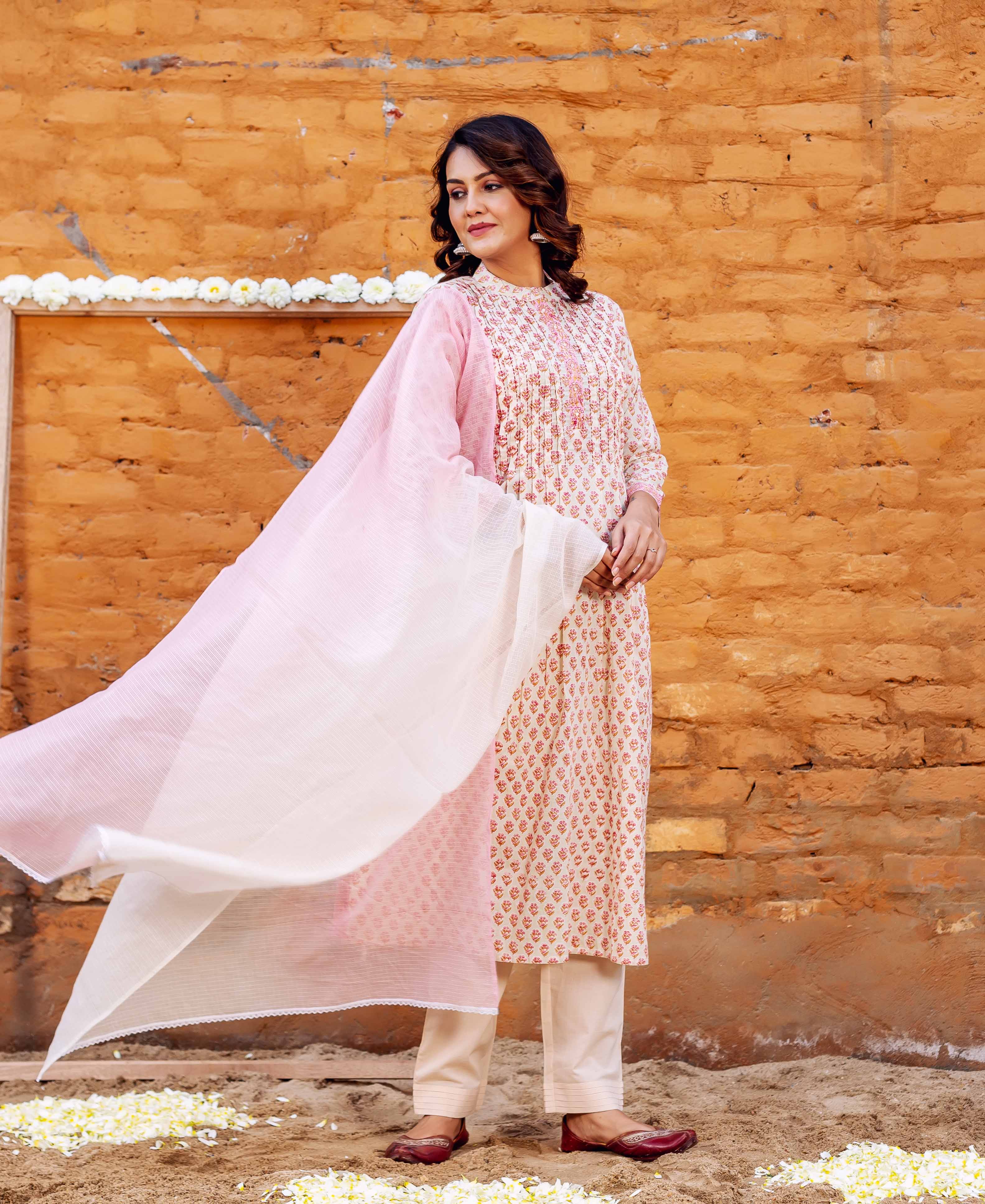 Model in full length block-printed cream and red kurta set with a flowy pink dupatta.