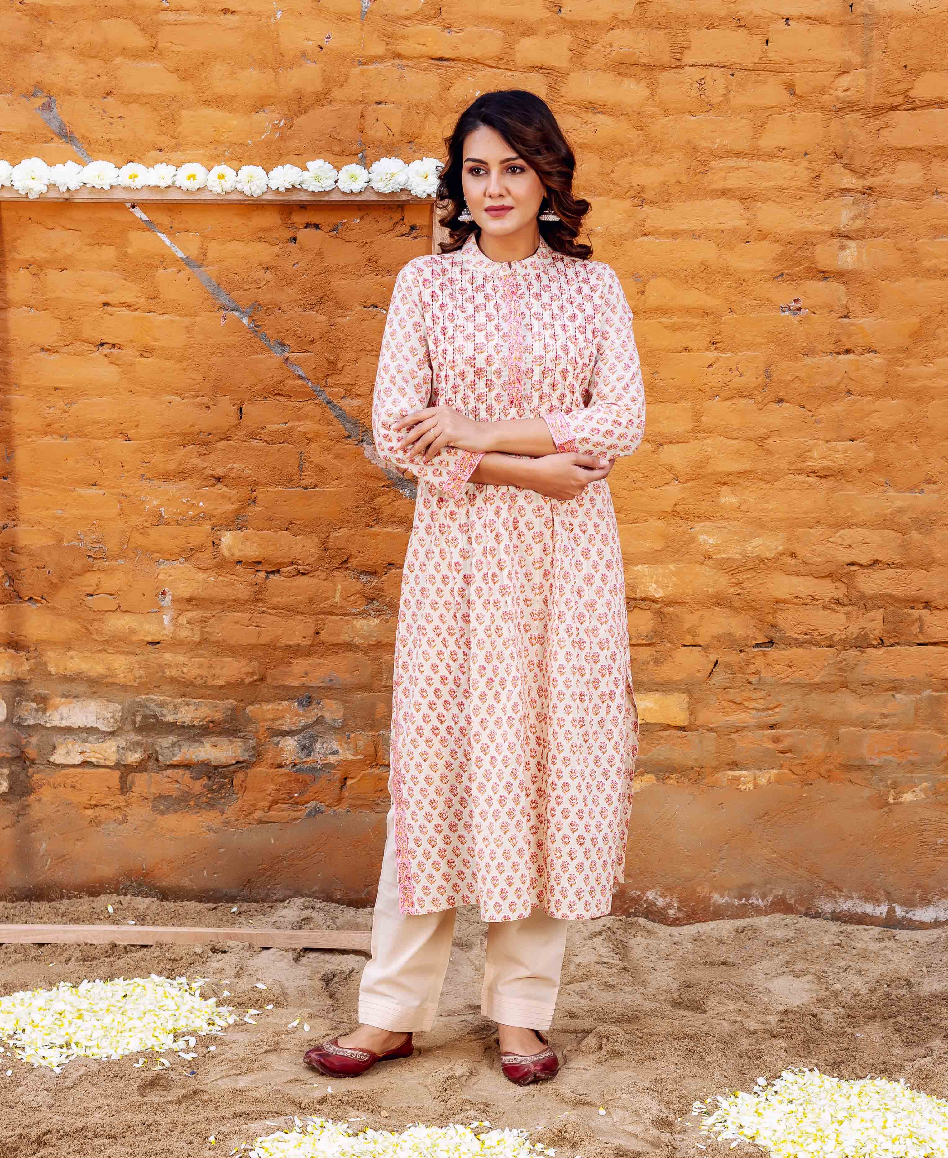 Front view of a woman in a cream block-printed straight cotton kurta with pink floral motifs.