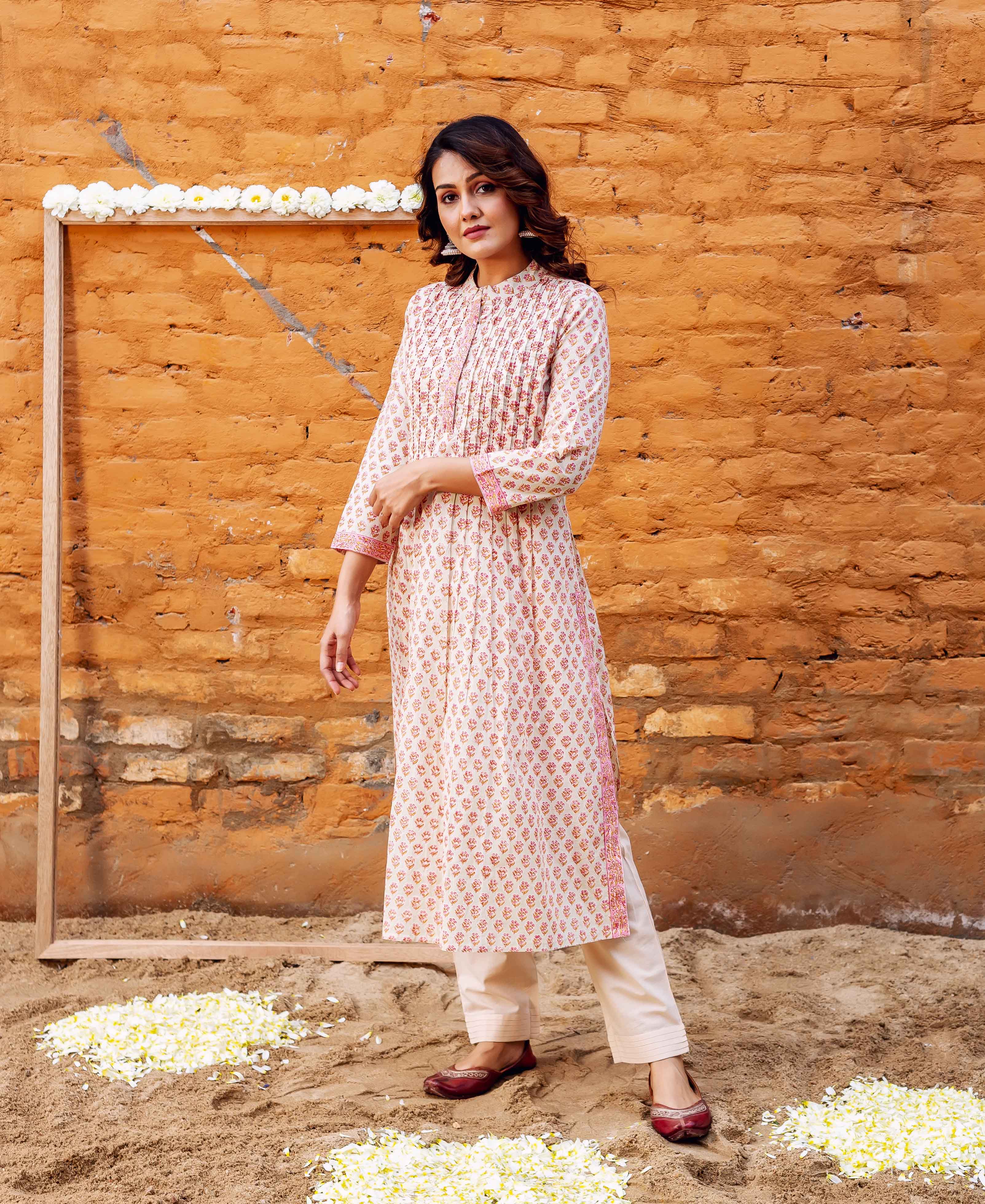 Model in cream straight cotton kurta with reddish-pink leafy block print and cream pants.