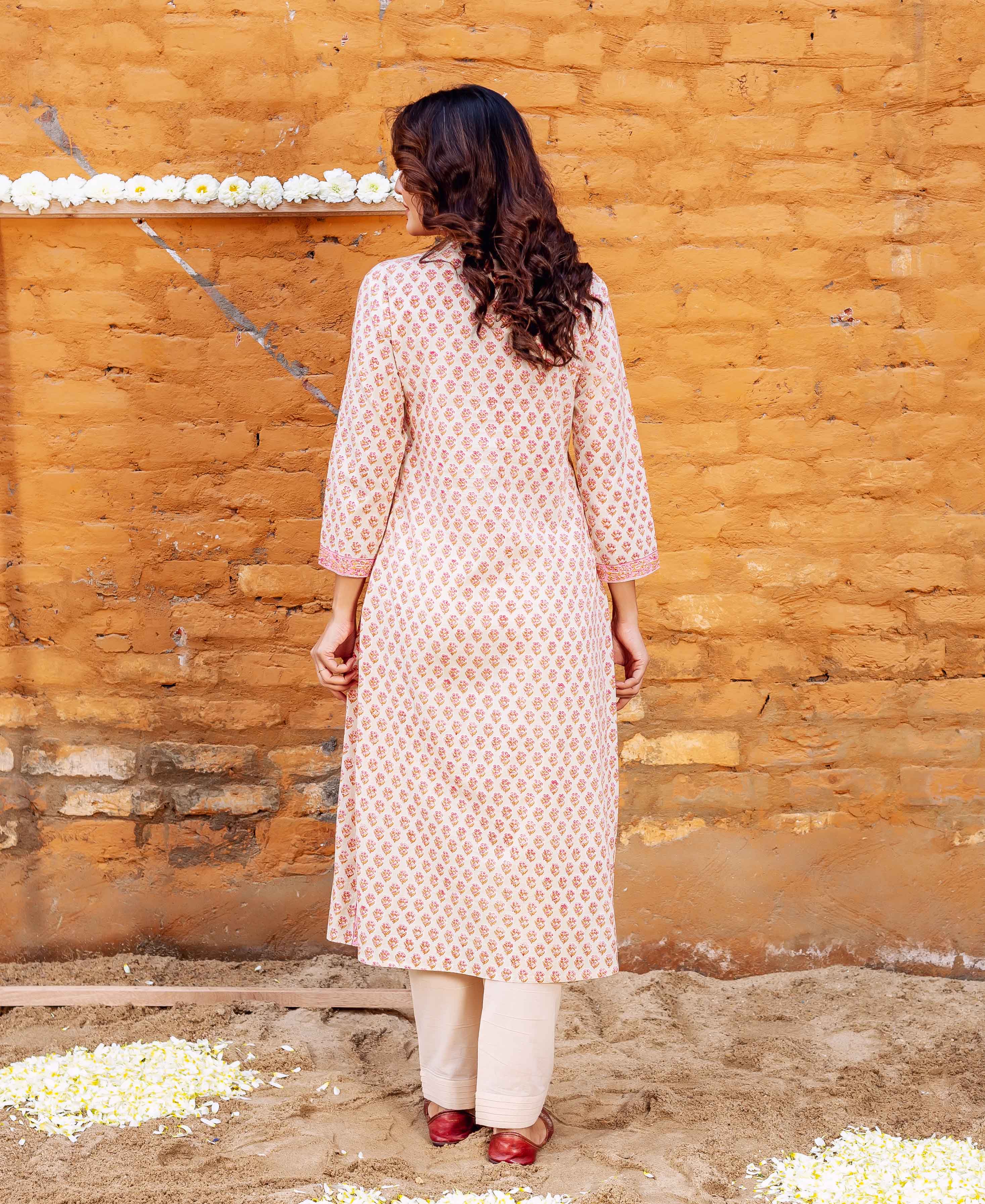 Back view model wearing off-white block-printed straight cotton kurta with pink motifs and beige pants.