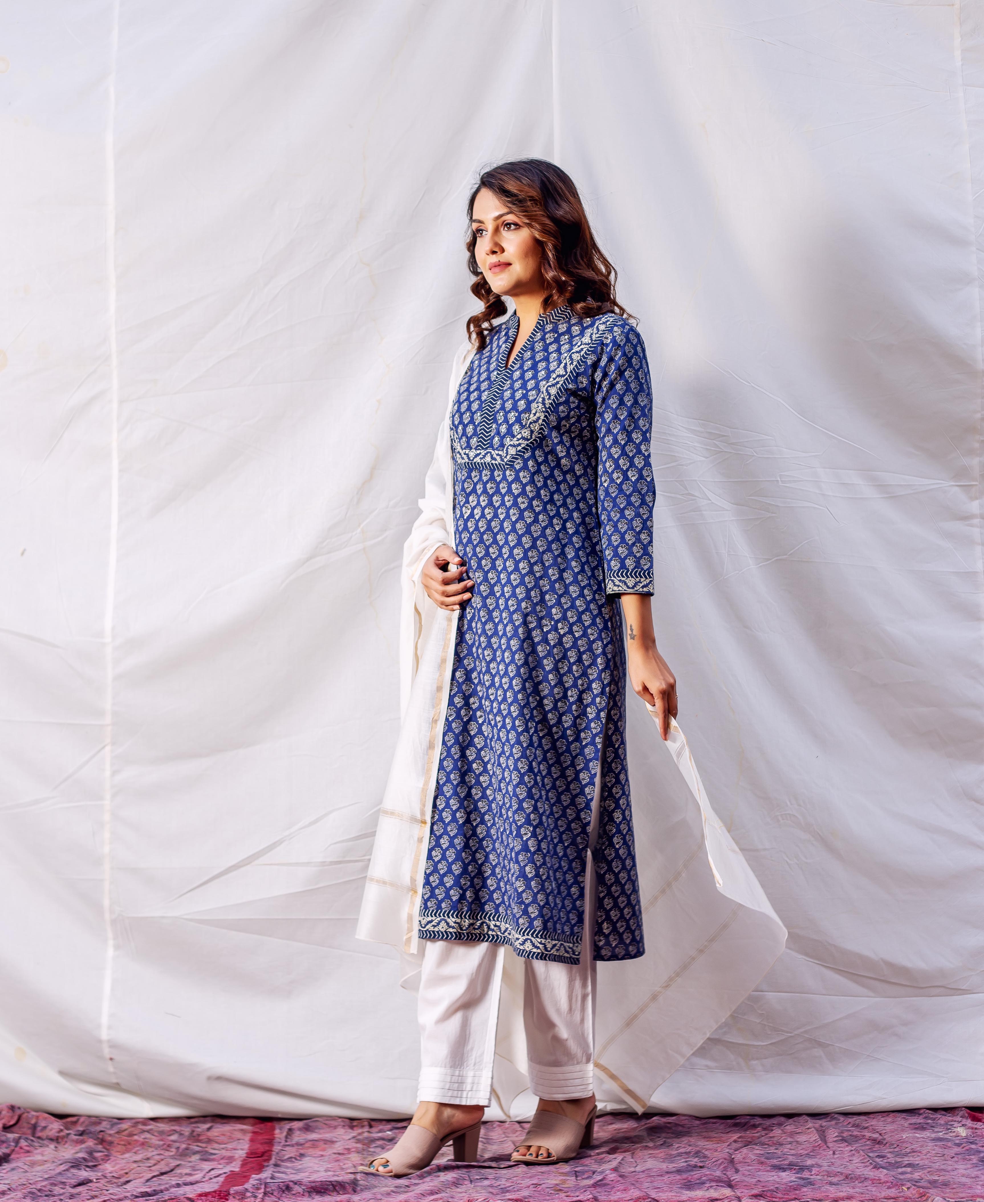 Woman models indigo hand block printed kurta, white embroidered yoke, white pants, and dupatta.