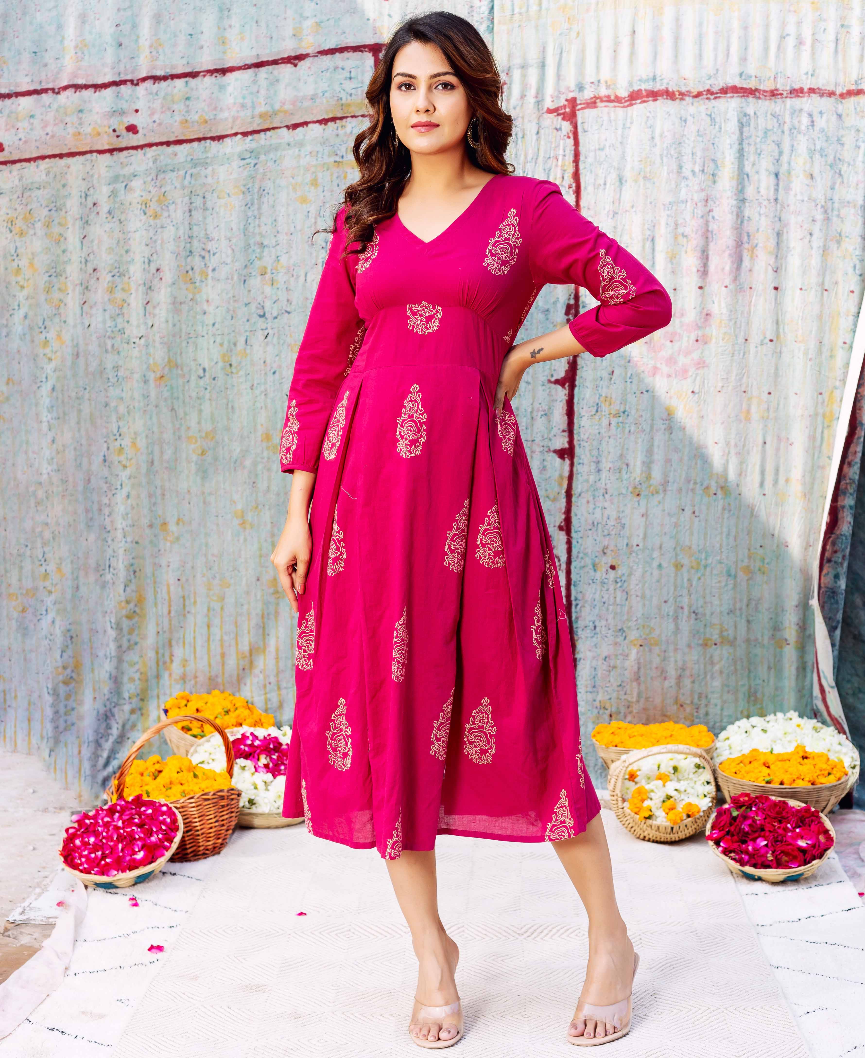 Woman wearing a hot pink Stella dress featuring golden hand-block ethnic patterns.
