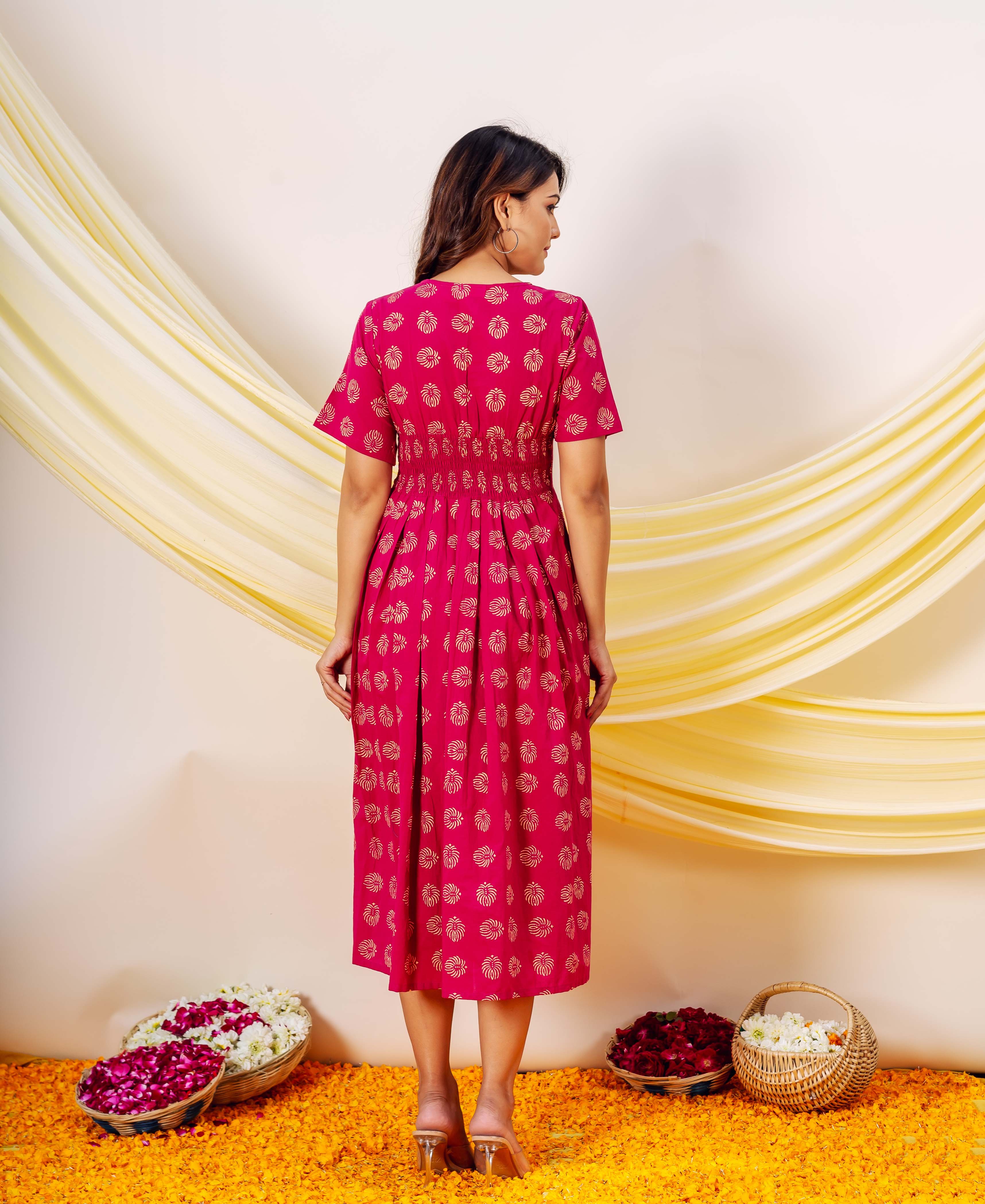 Back view of model in a fuchsia midi dress with golden hand-block-printed motifs.