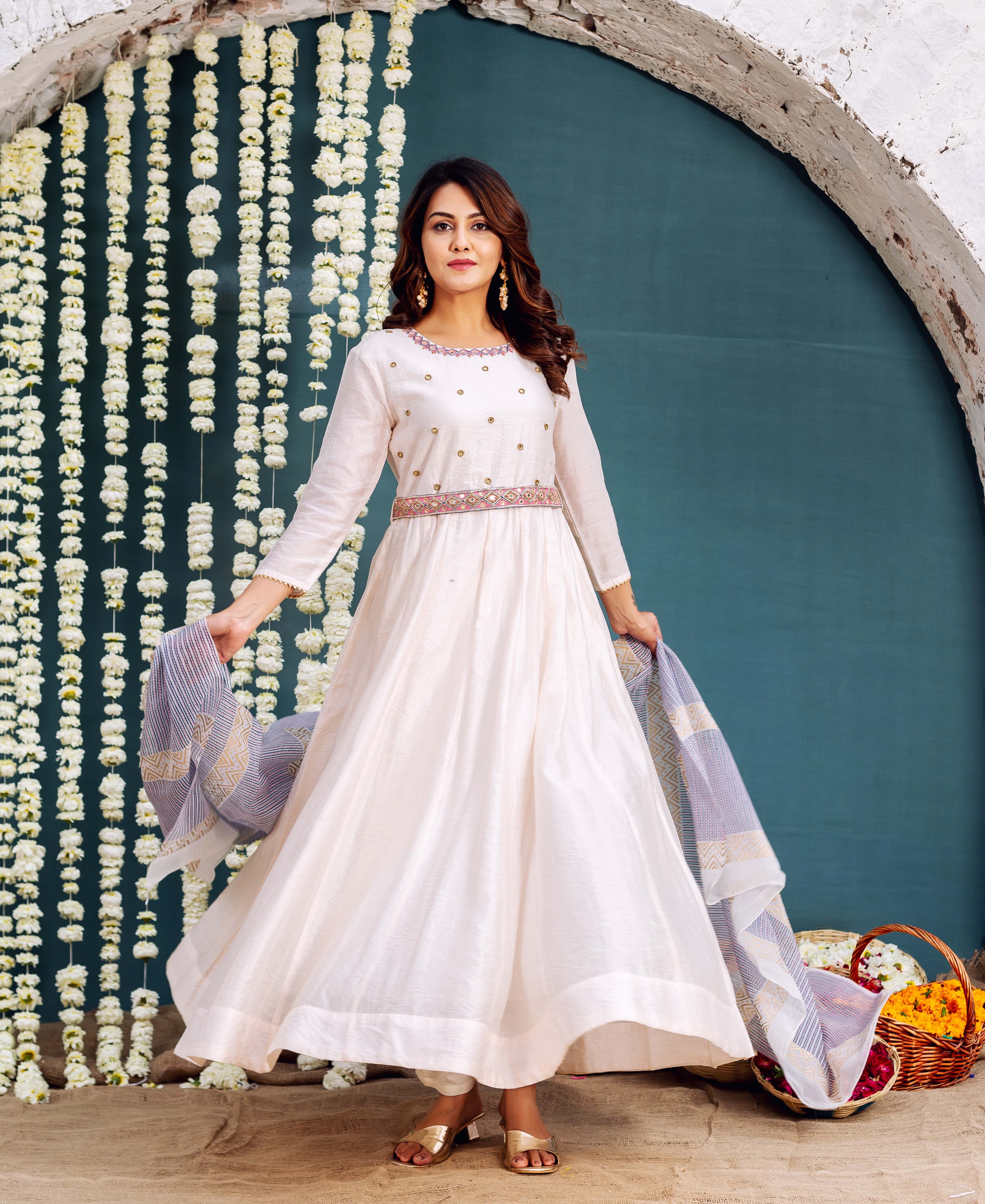 Full-length model wears cream ethnic Anarkali dress with embroidered neckline and patterned belt.