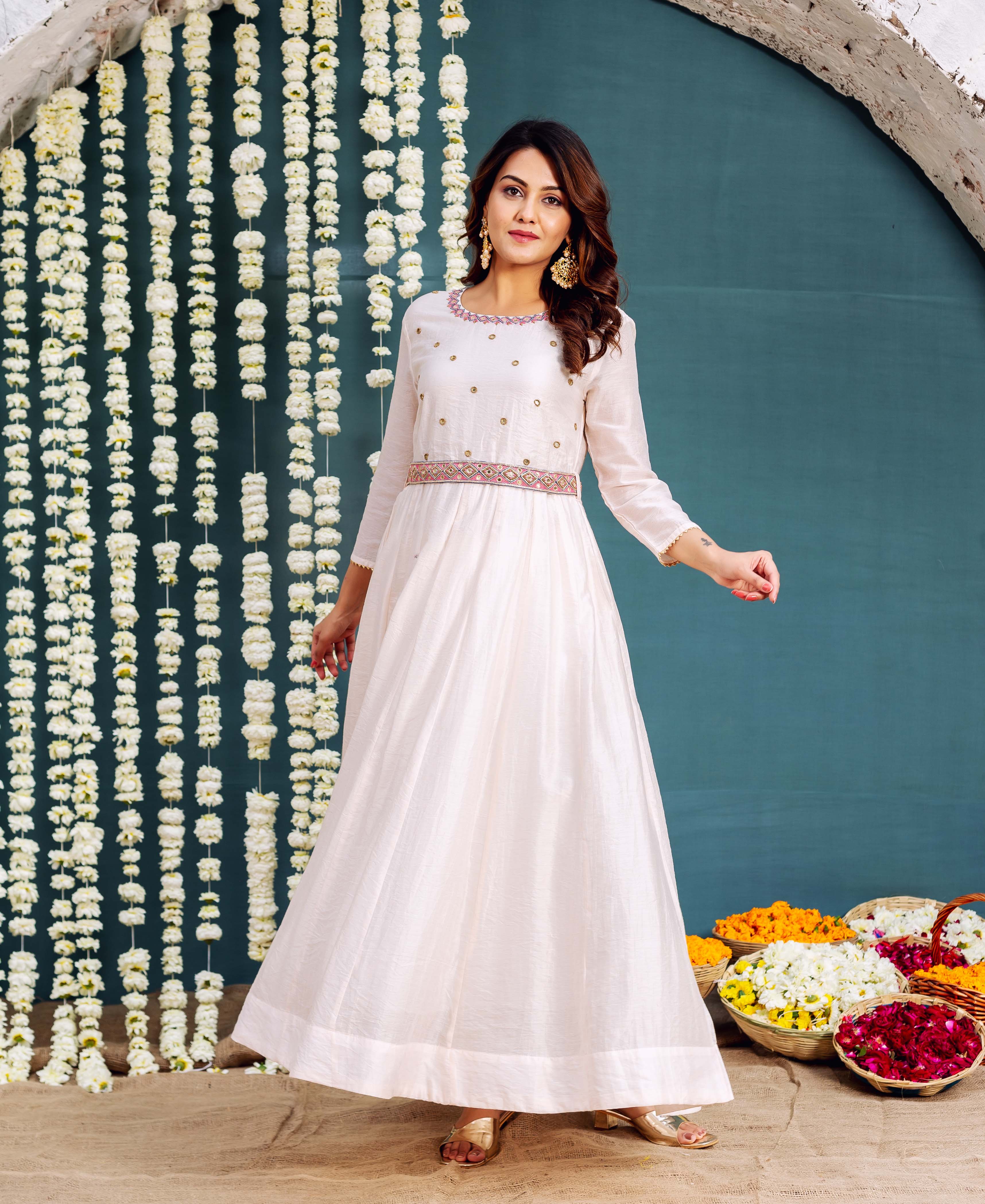 Model wearing an off-white Anarkali dress, featuring golden embroidery and a patterned waist belt.