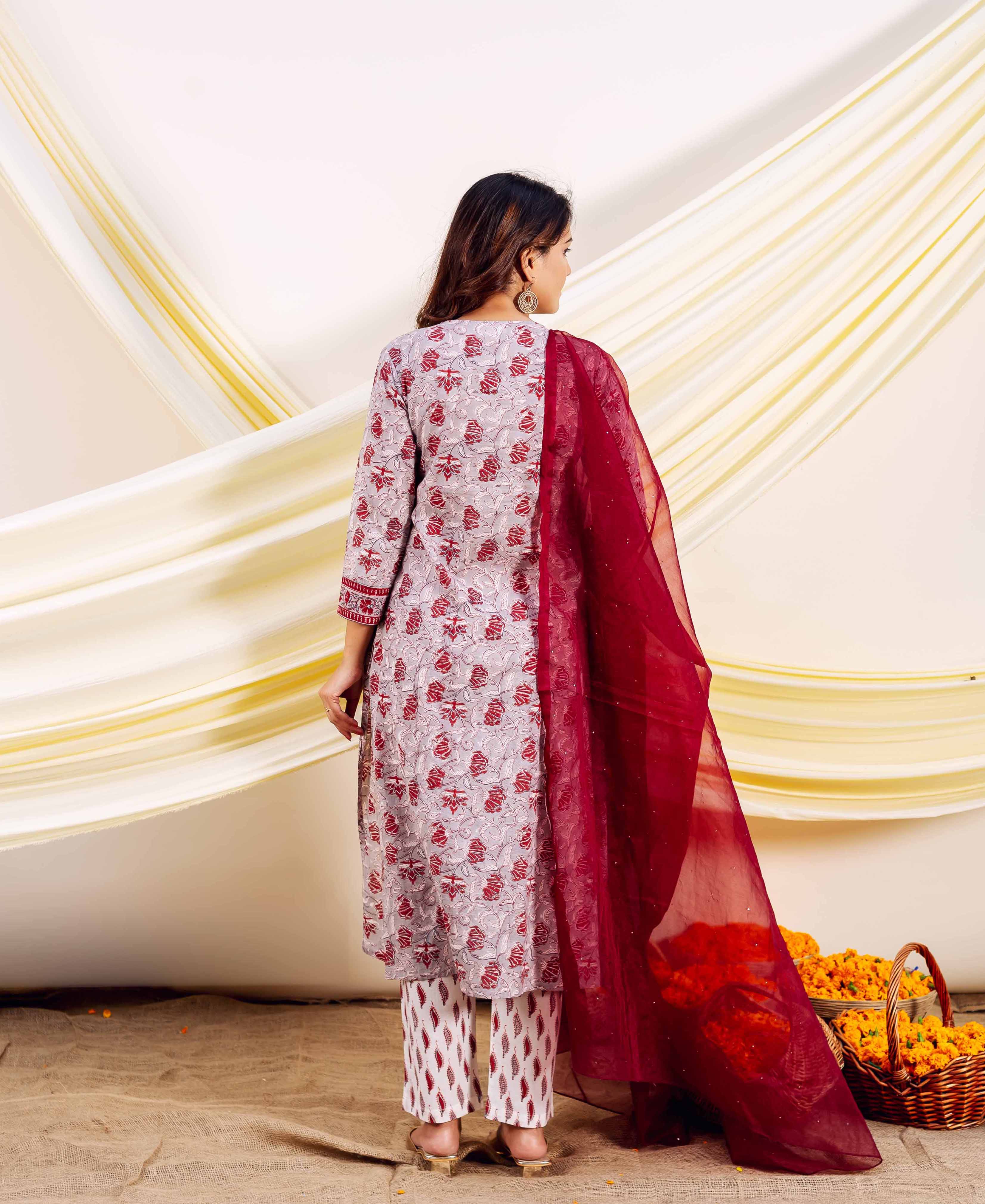 Rear view: Model wearing grey kurta with red floral print, white patterned pants, and maroon dupatta.