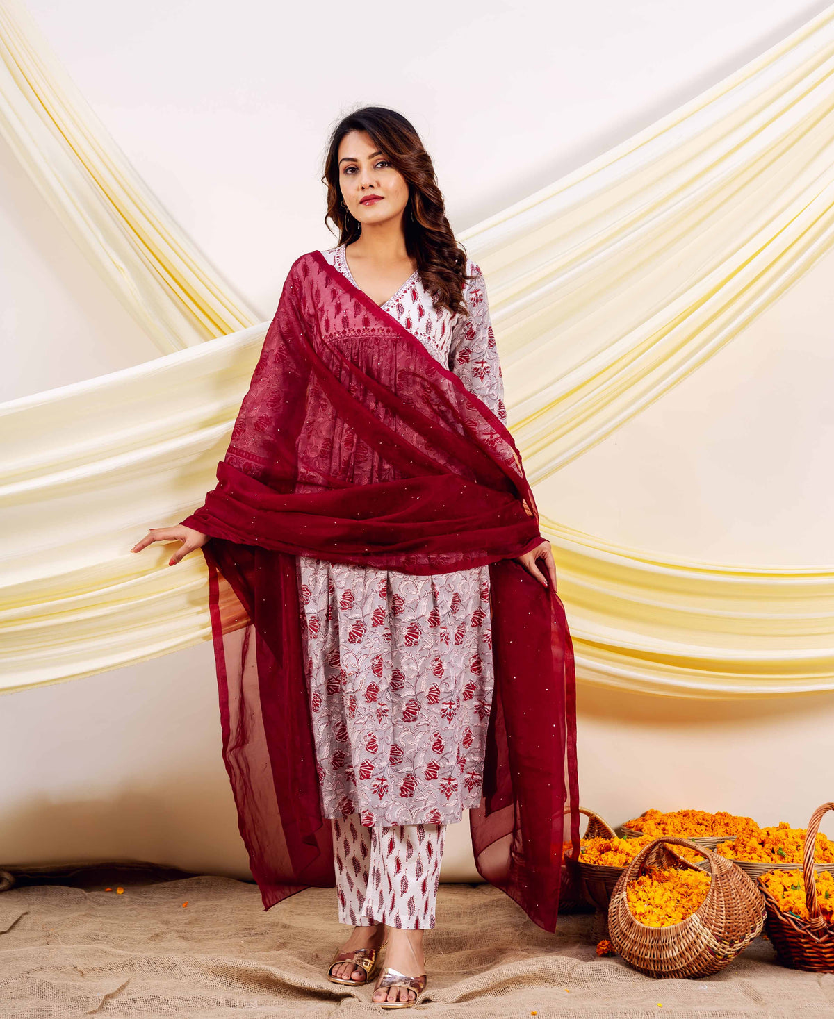 Woman wearing grey and red hand-block-printed kurta with matching pants and red dupatta.