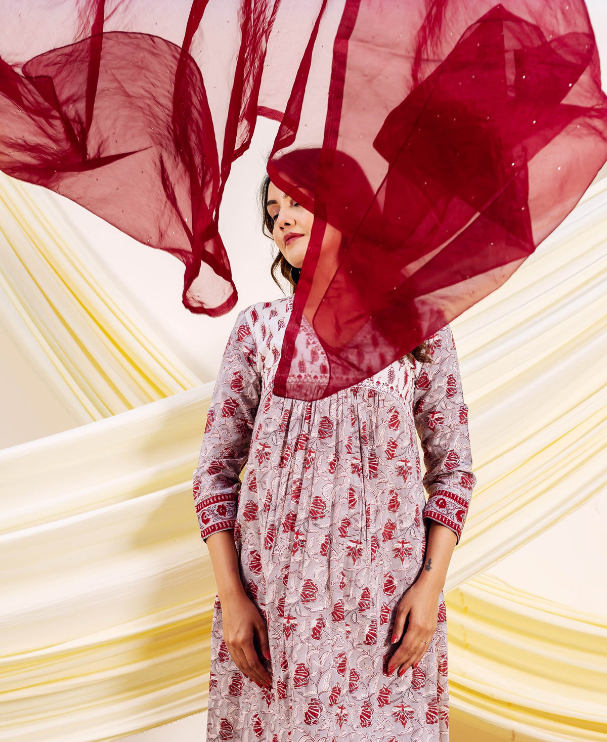 Front view of model in a grey and red floral hand-block printed kurta with red dupatta.