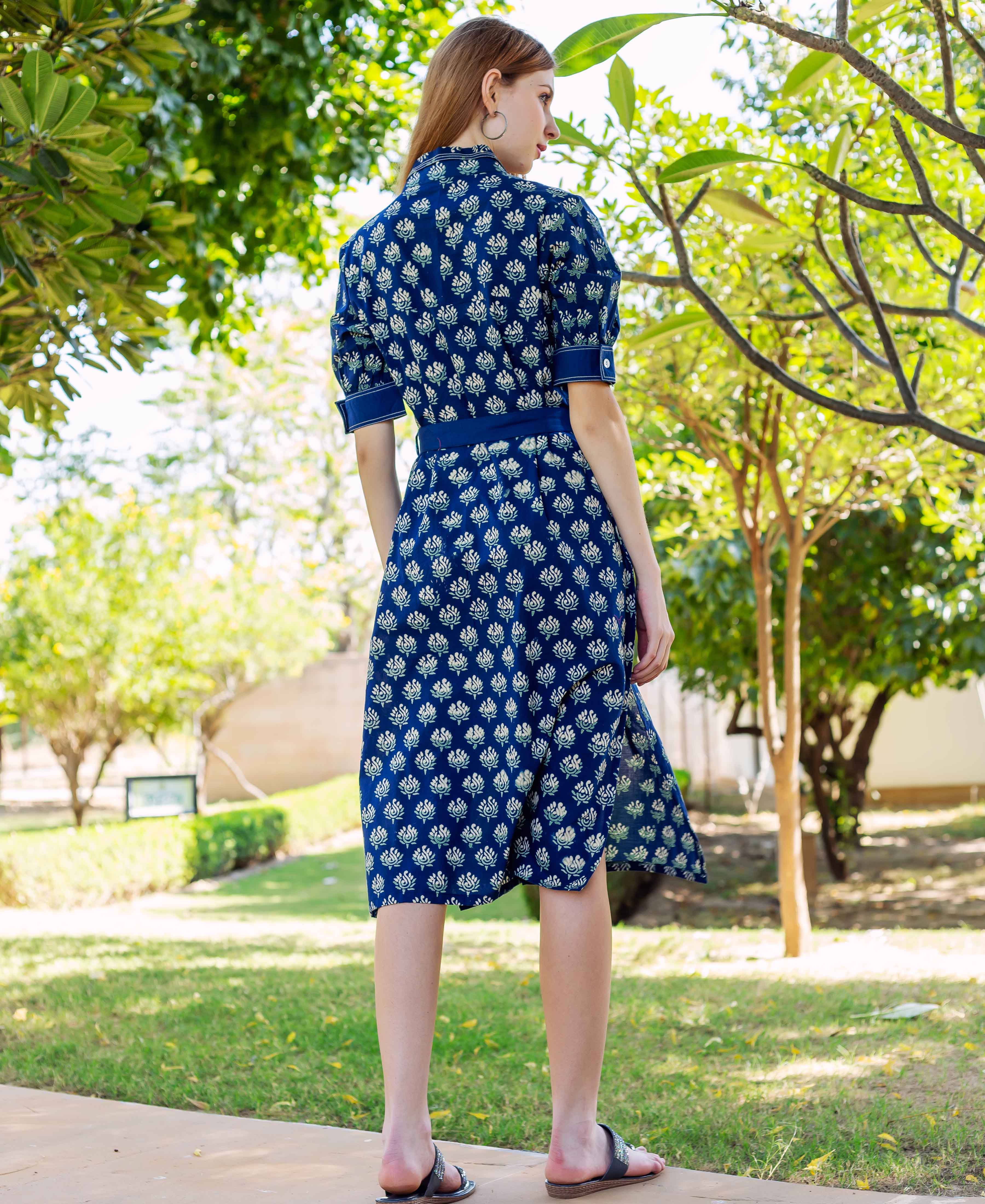 Model from back in indigo hand block printed knee-length dress with white and green florals.