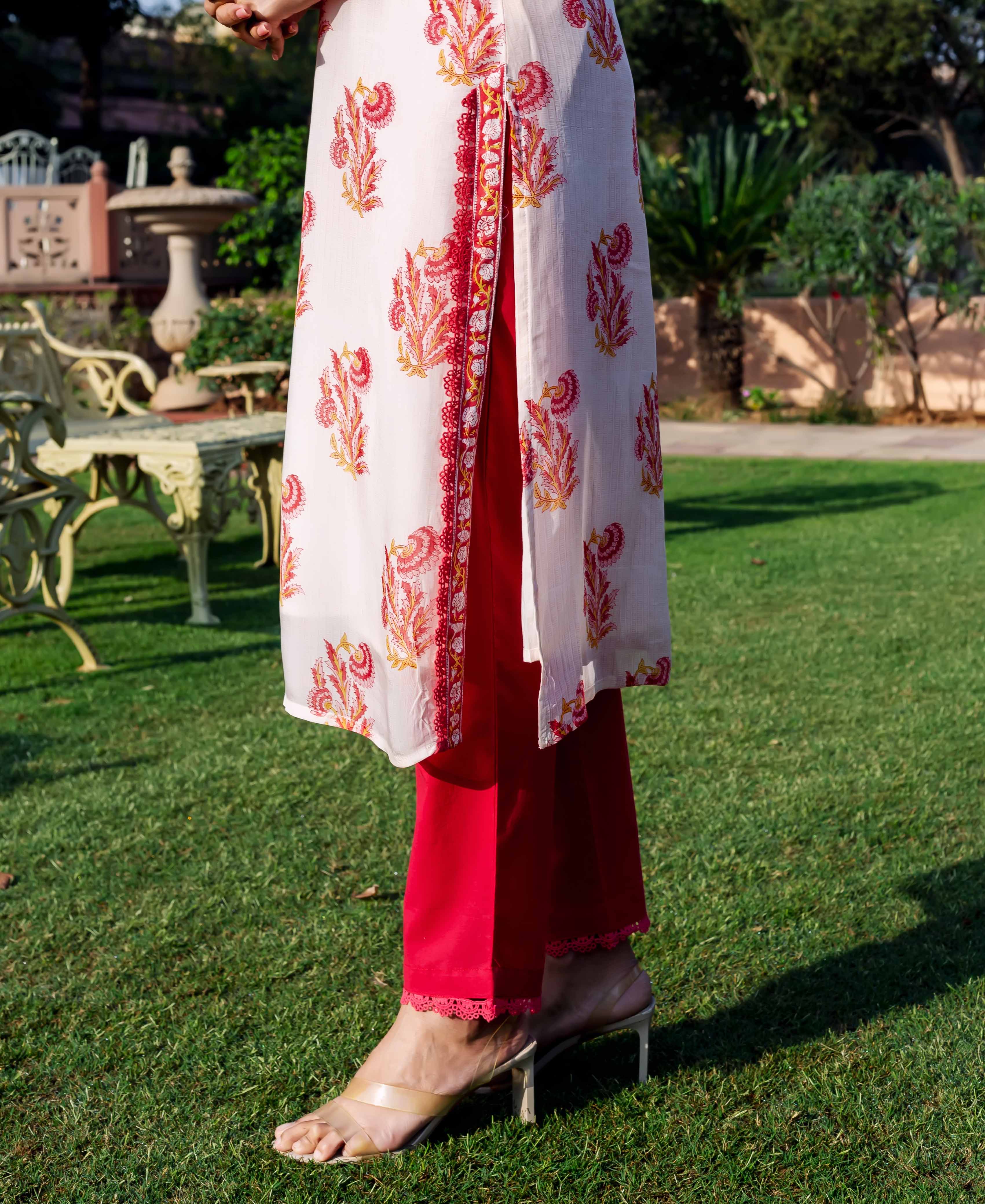 Model wears off-white organza kurta with red ethnic print, red pants, clear heels.