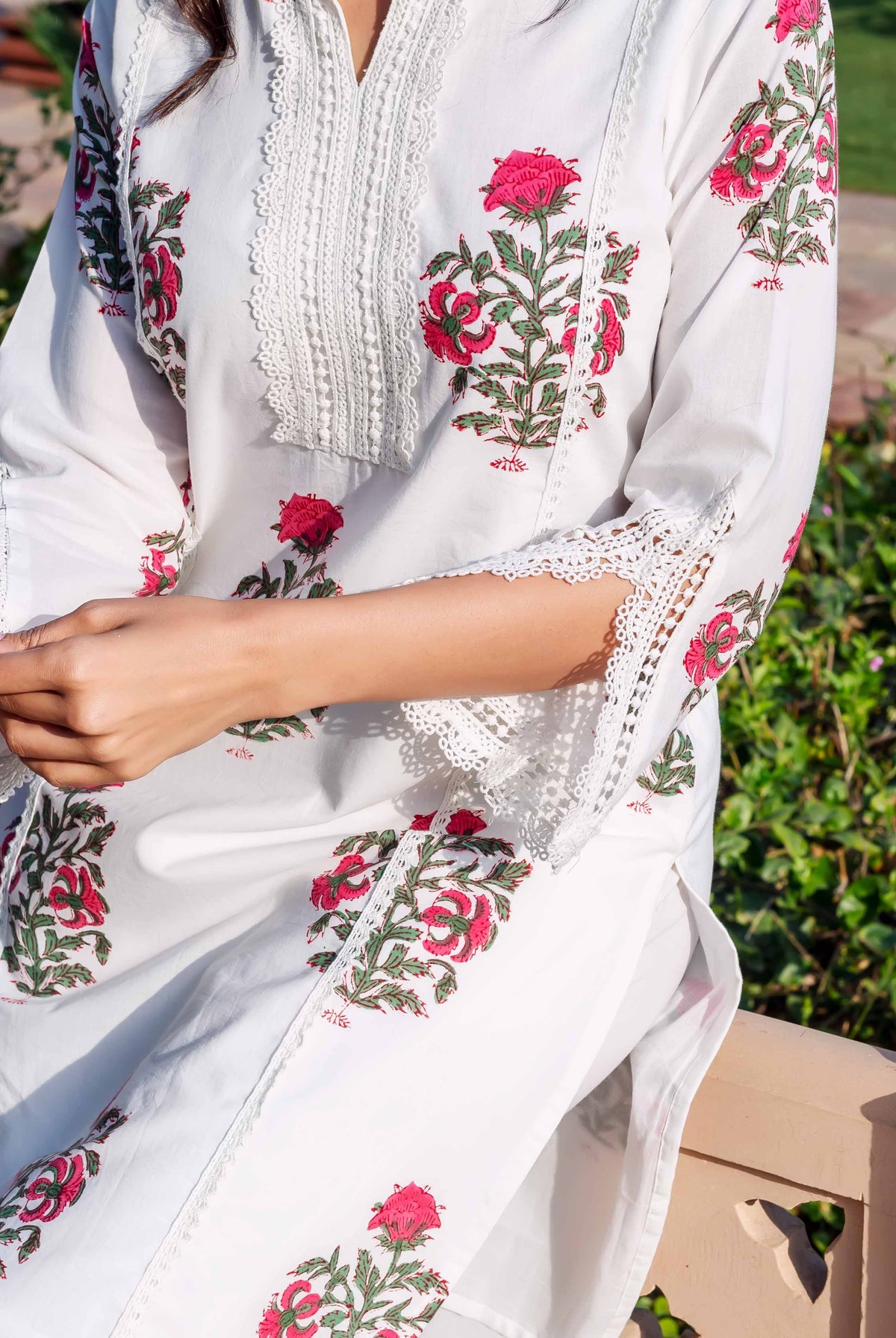 A model wearing a white cotton kurta with red floral block prints and lace trim.