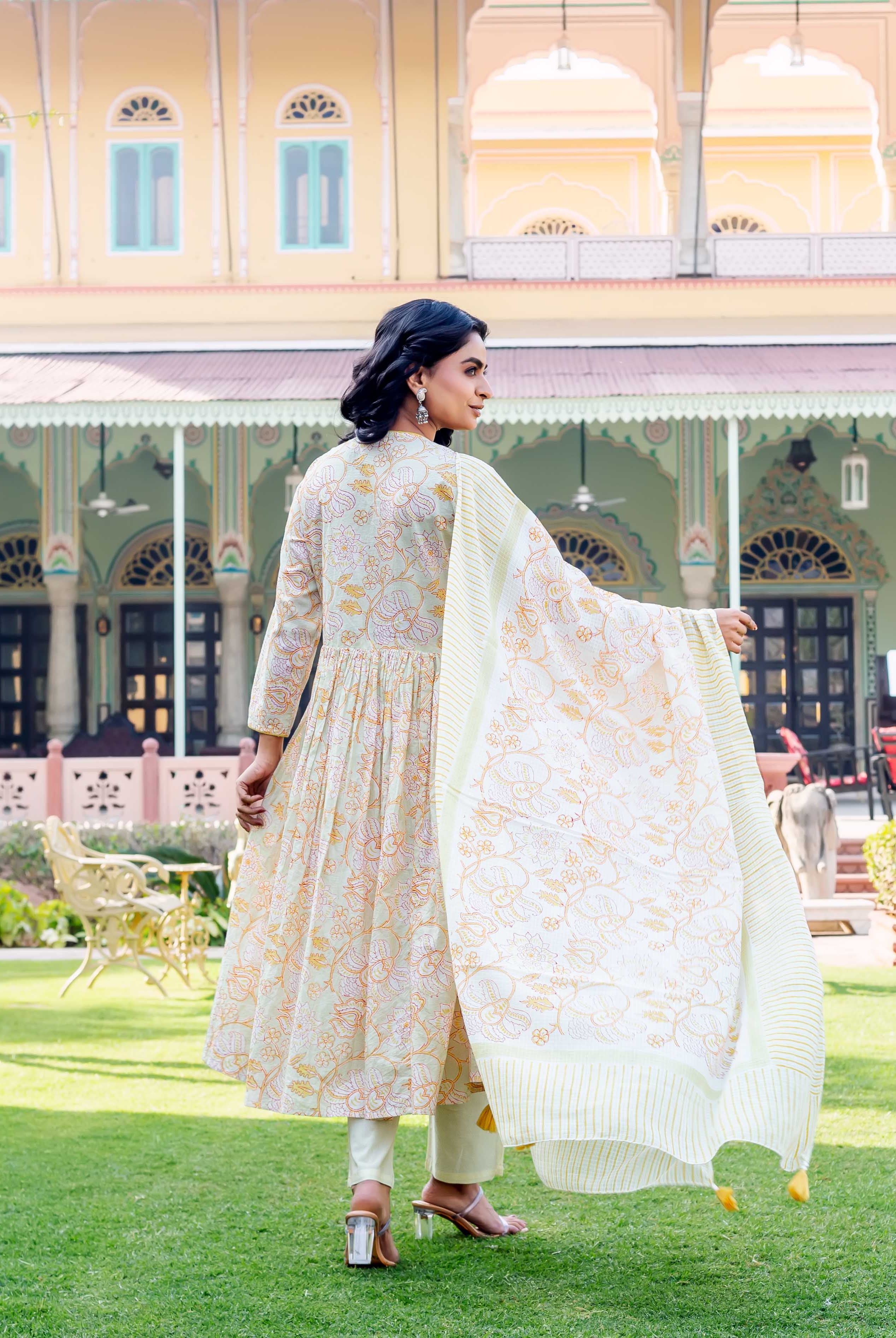 Back view: woman in light green floral block print kurta with yellow striped dupatta.
