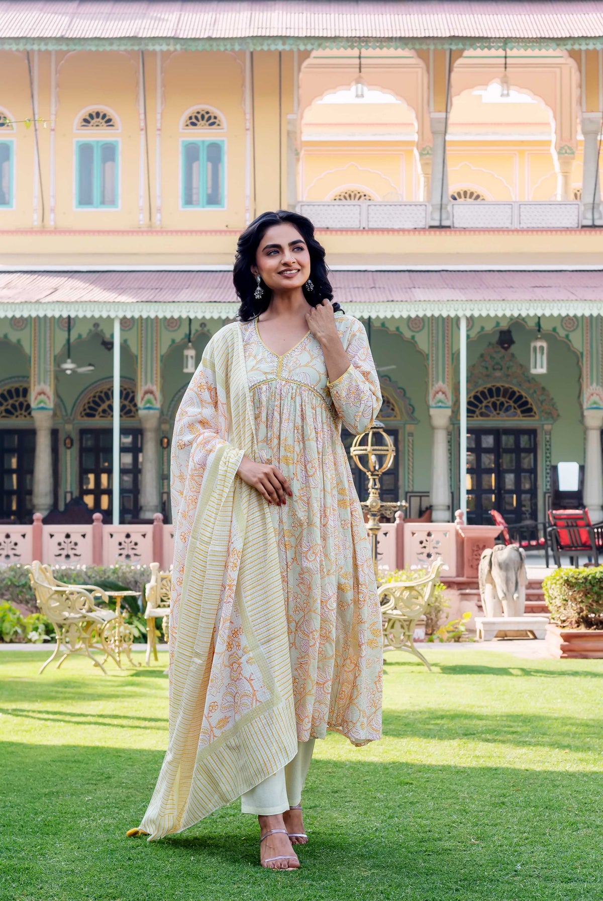 Model in a cream floral hand-block printed kurta with matching pants and dupatta.