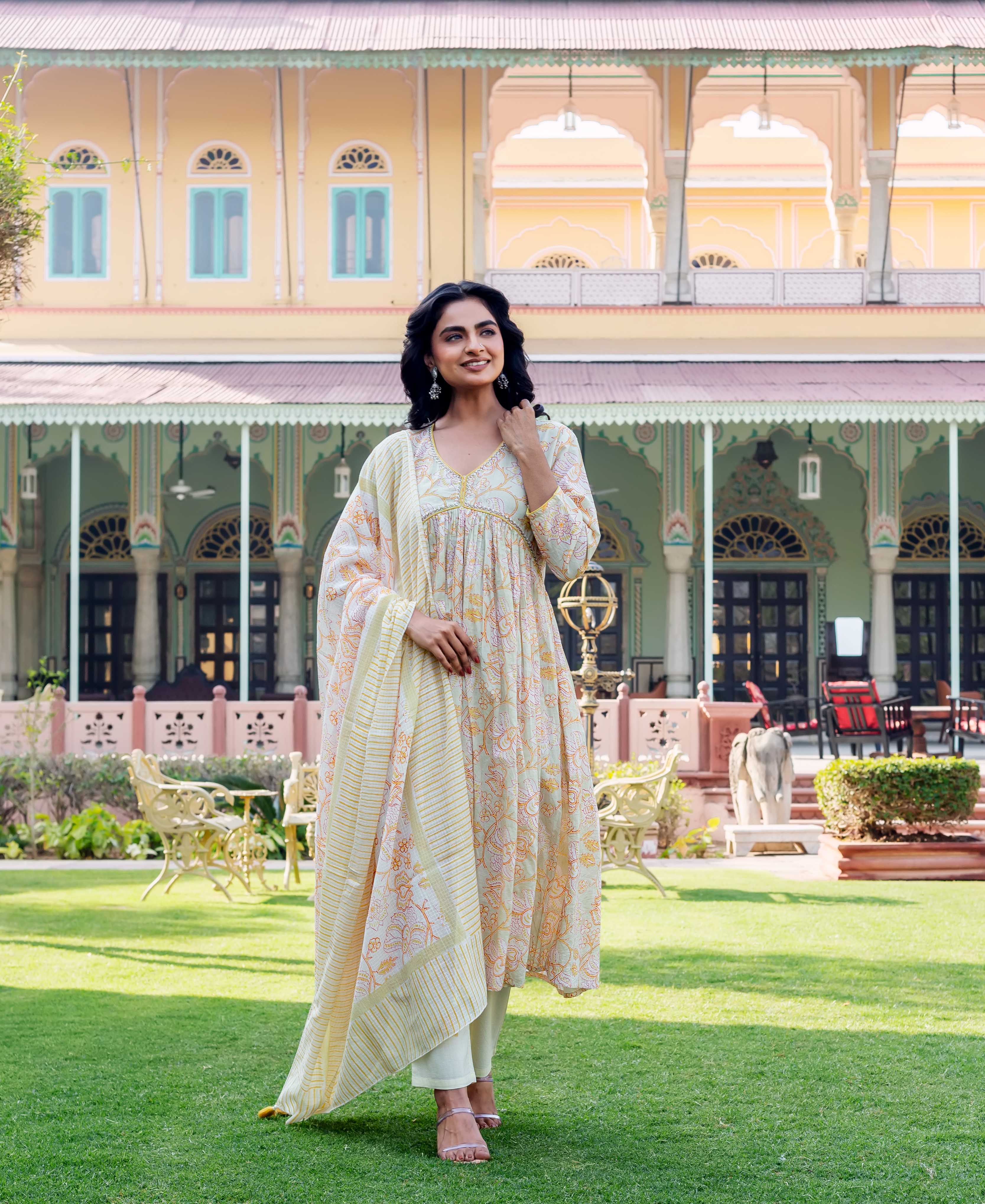 Model in a cream floral hand-block printed kurta with matching pants and dupatta.