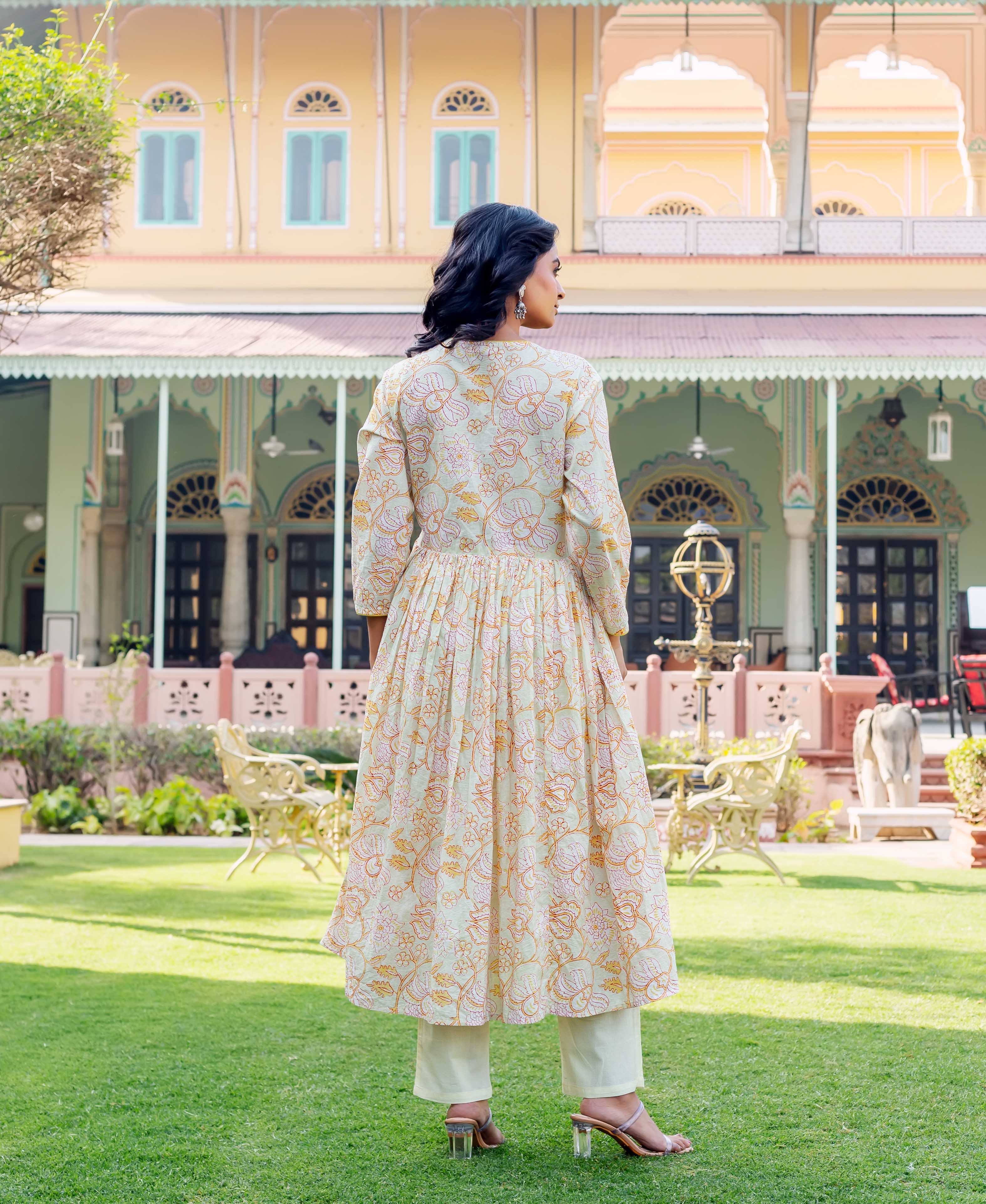 Rear view of model in pale green hand-block printed floral cotton kurta and cream pants.