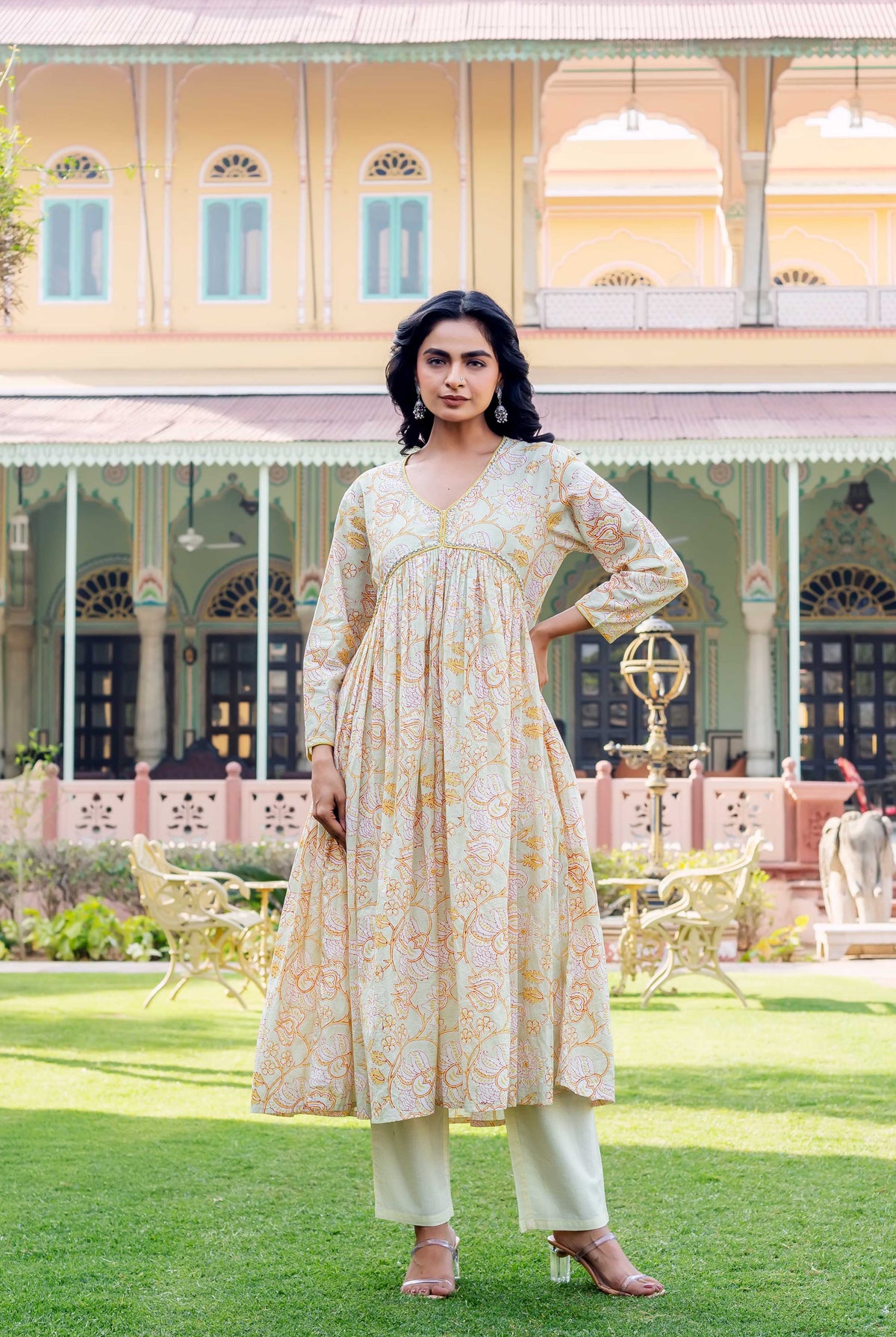 Model wears a pale green hand-block printed kurta with orange floral print and light green pants.