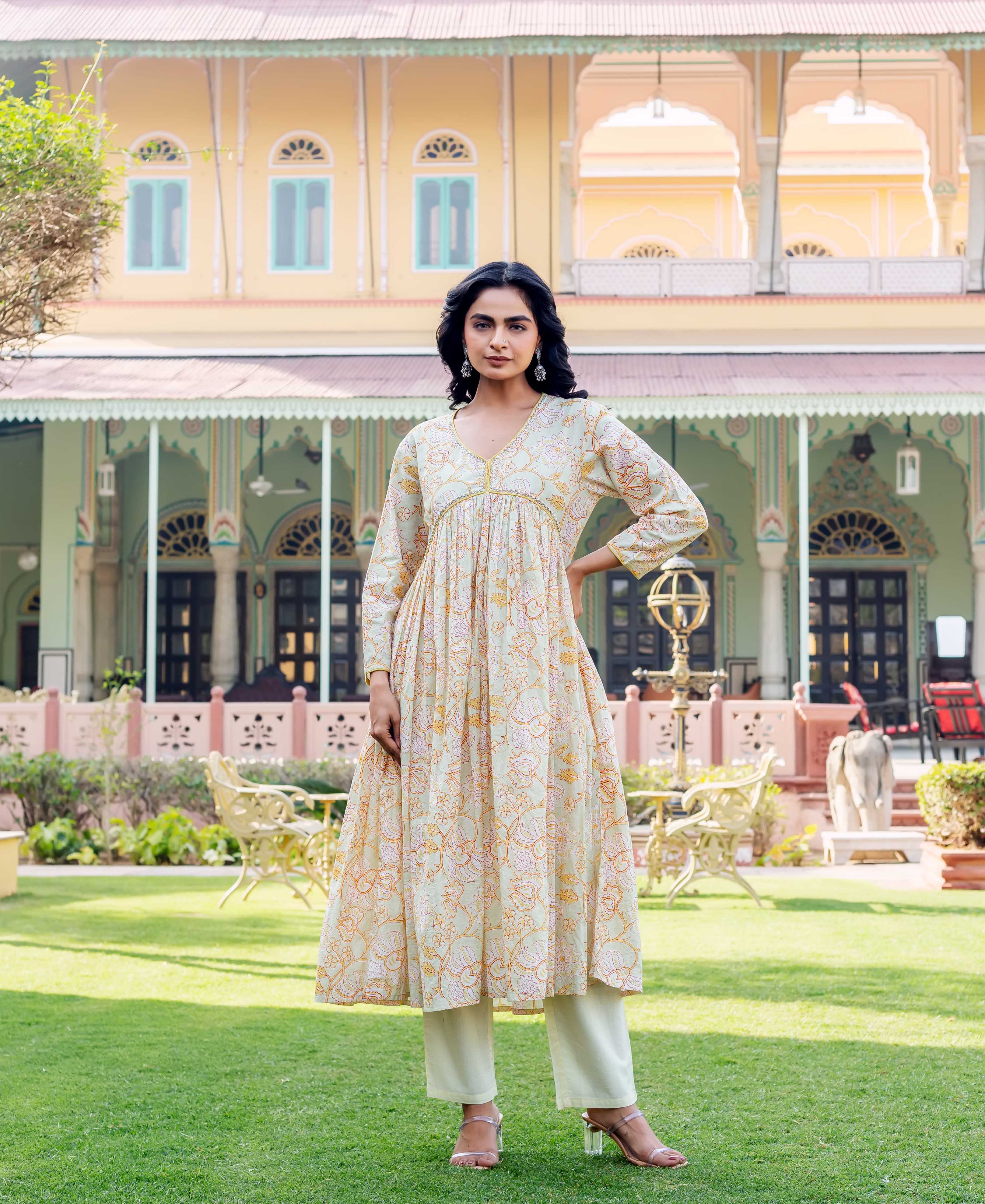 Model wears a pale green hand-block printed kurta with orange floral print and light green pants.
