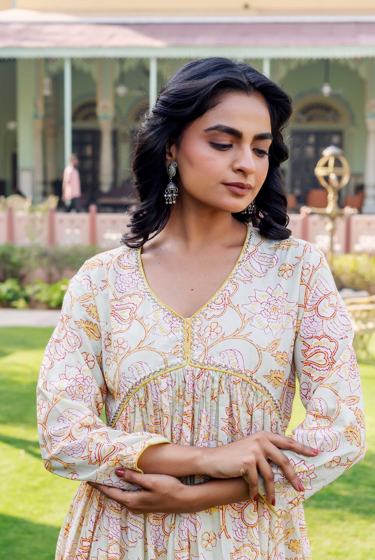 Model in a pale floral kurta with red-yellow patterns, V-neck, and gathered empire waist.