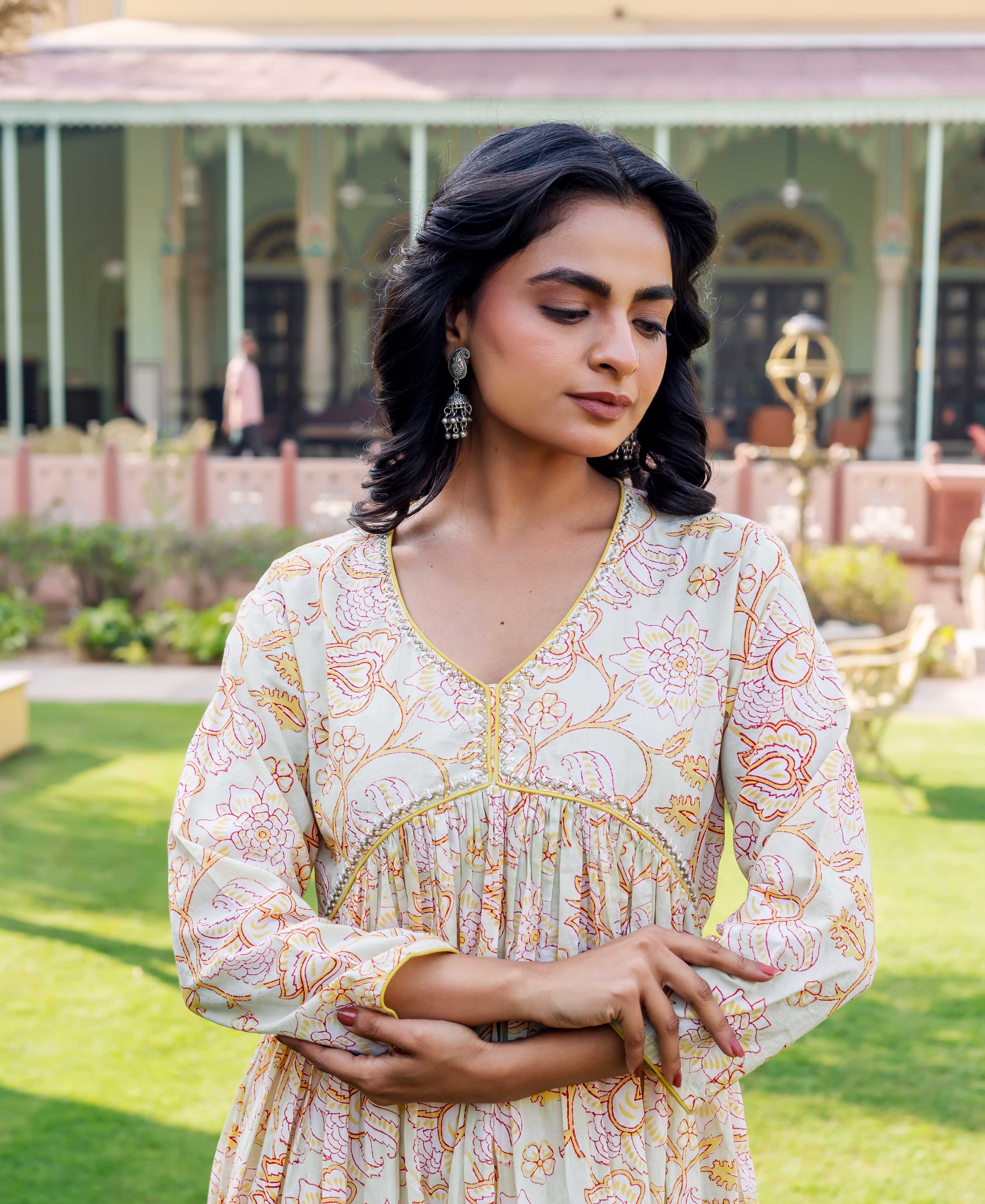 Model in a pale floral kurta with red-yellow patterns, V-neck, and gathered empire waist.