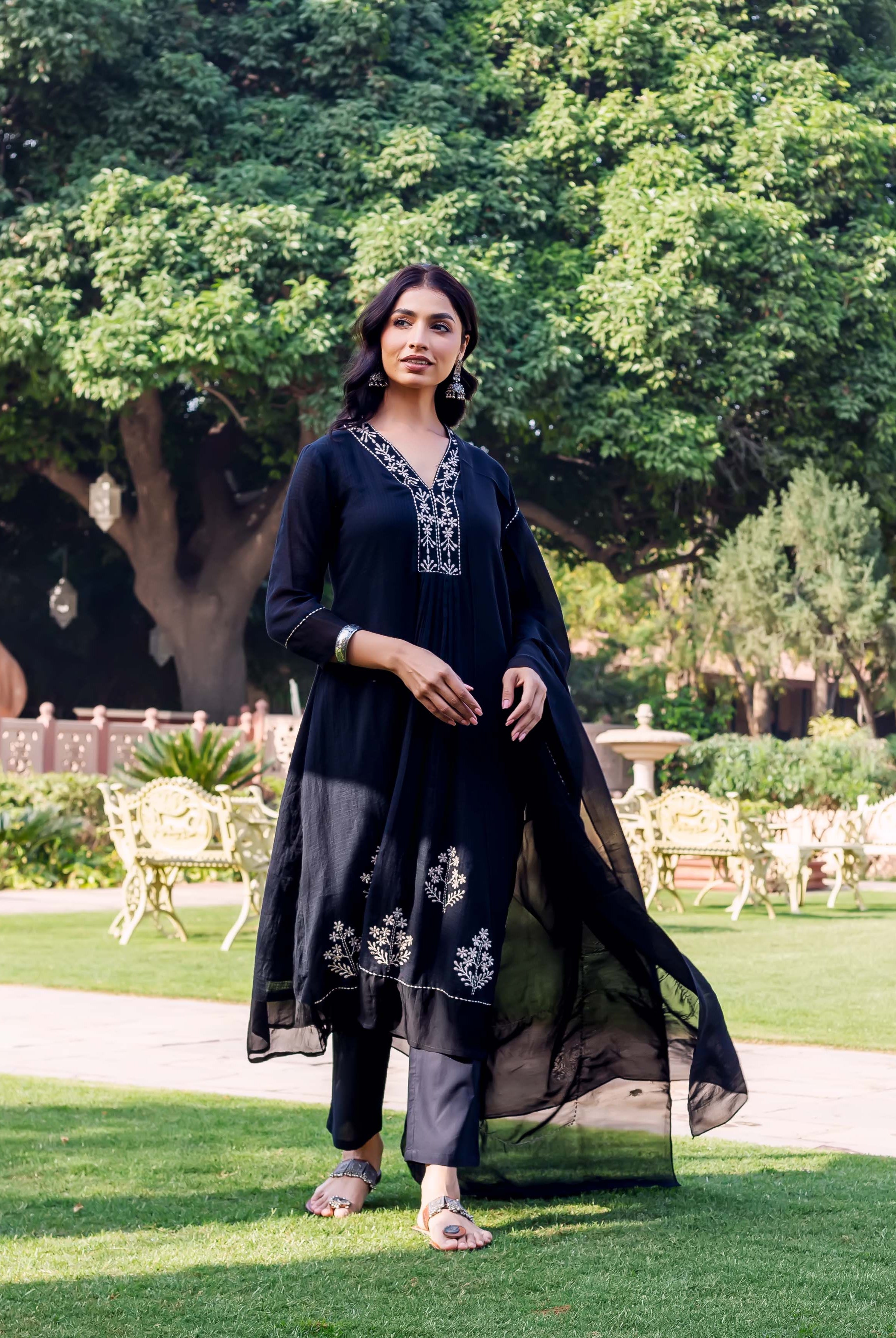 Model in full-length black kurta set with white floral embroidery on neckline and hem.