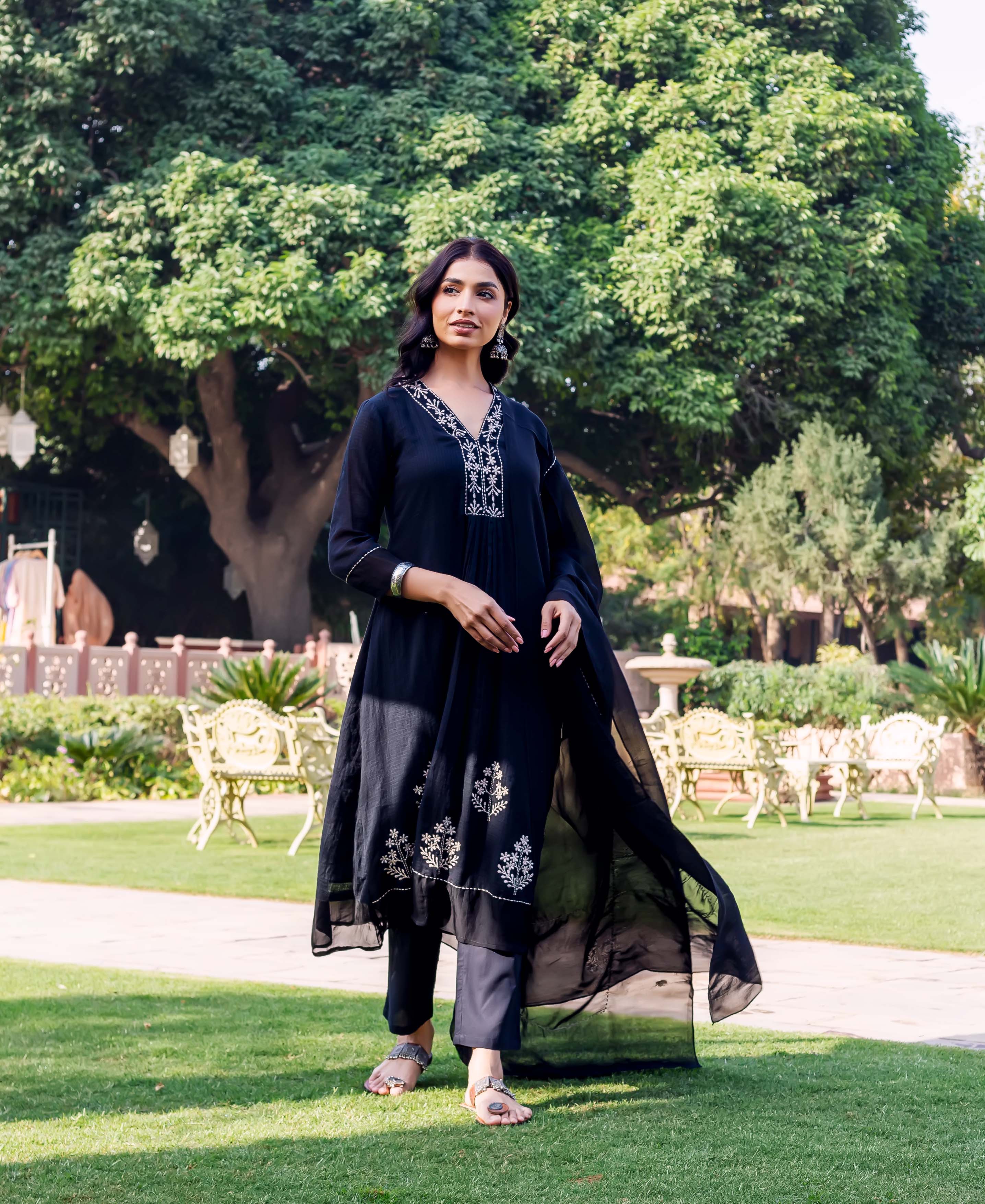 Model in full-length black kurta set with white floral embroidery on neckline and hem.