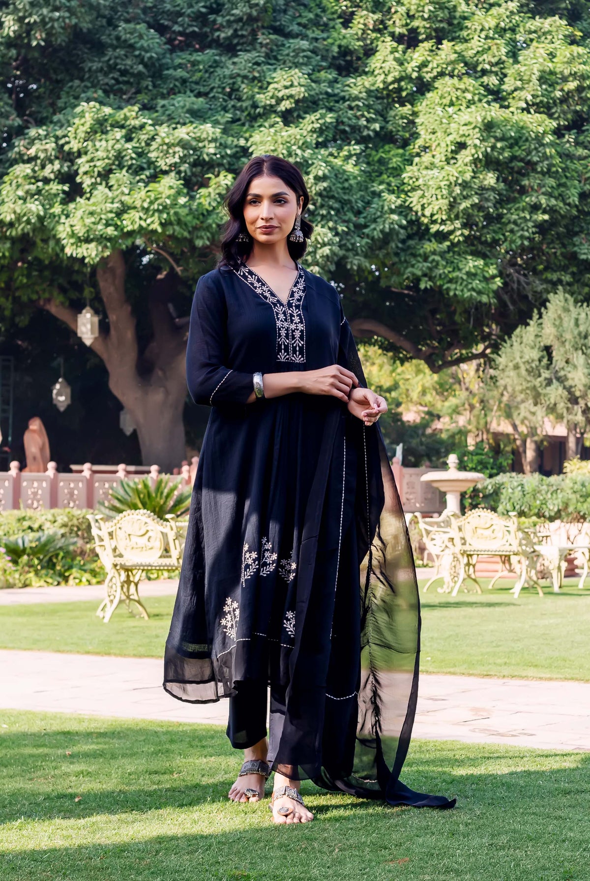 Woman models a black ethnic kurta set with white embroidered V-neck and lower patterns.