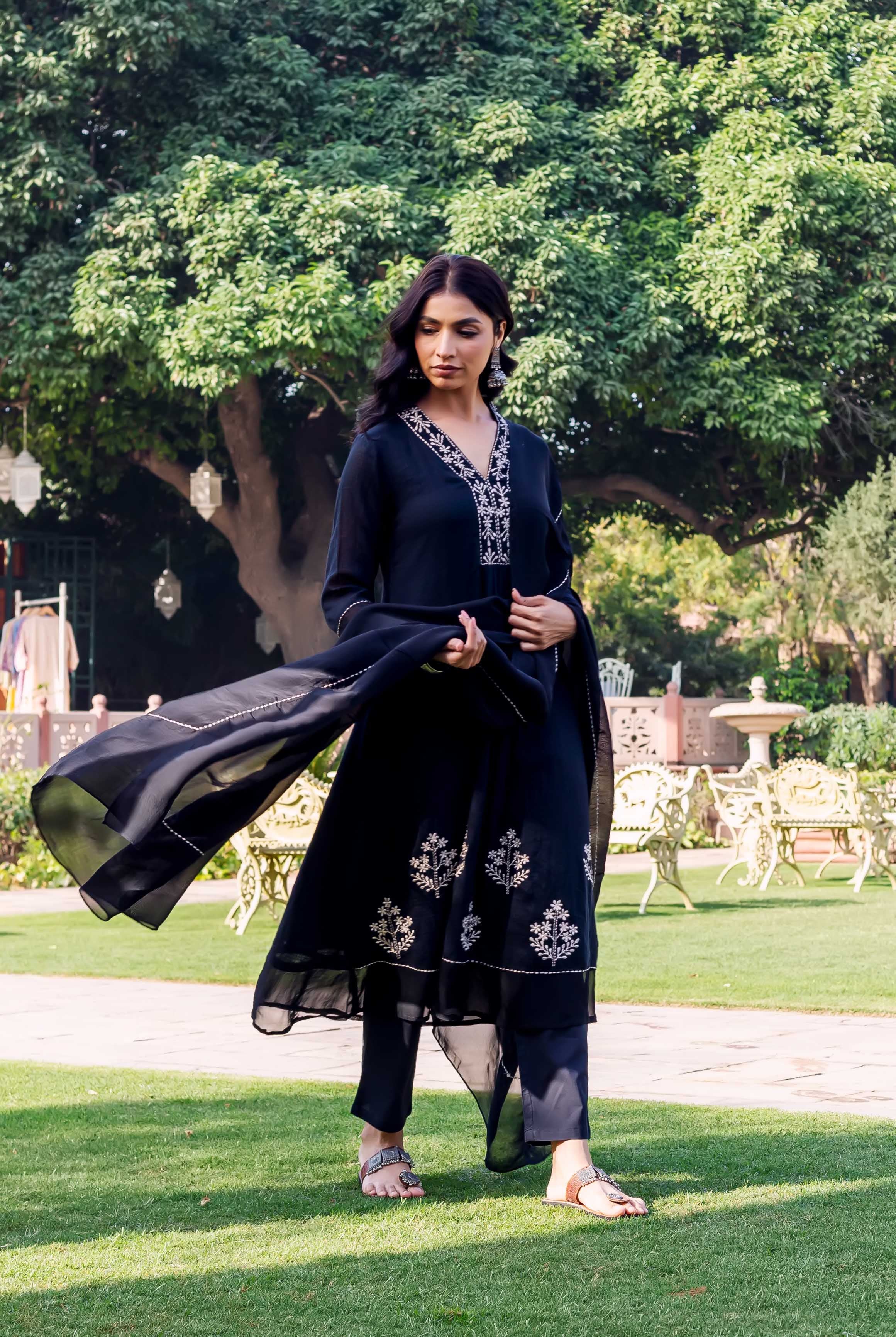 Model in black hand-block printed kurta set with white floral motifs on green grass.