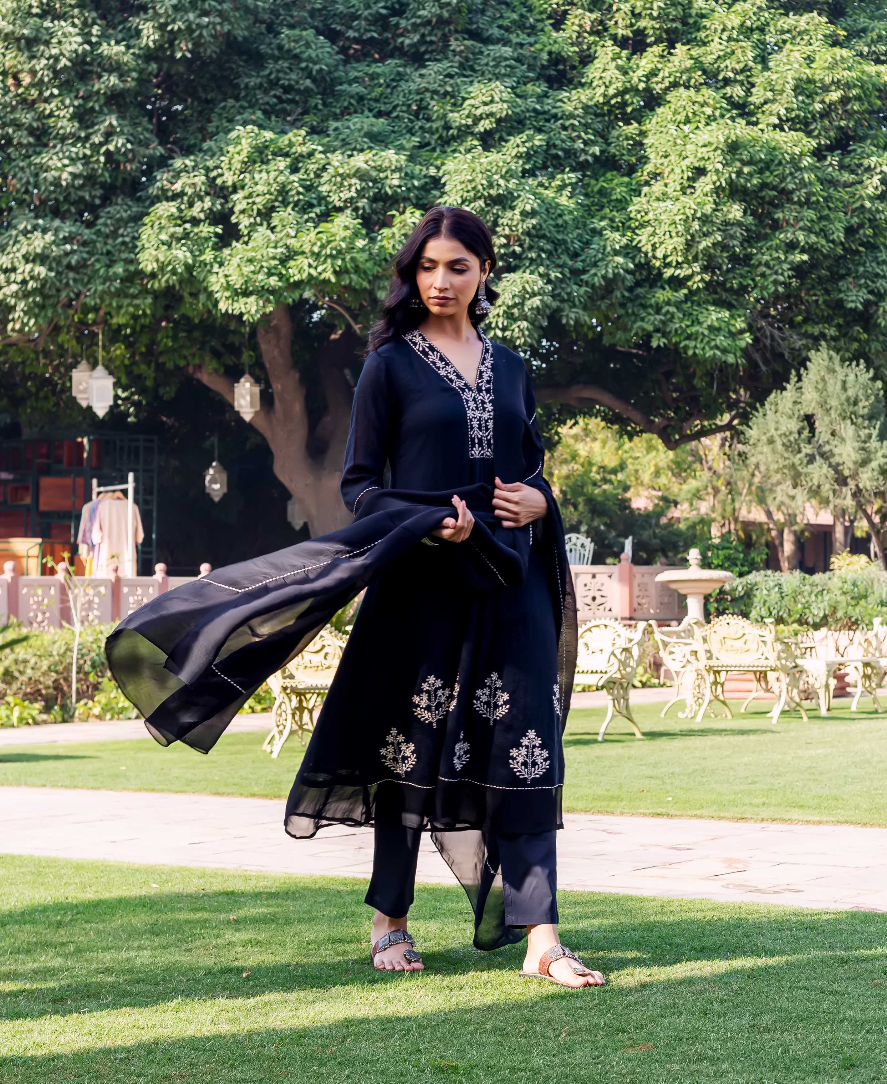 Model in black hand-block printed kurta set with white floral motifs on green grass.