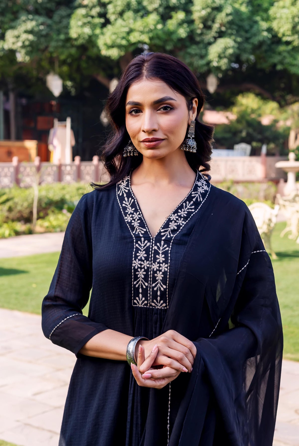 Front view of a woman in a black kurta with intricate white embroidered V-neck.