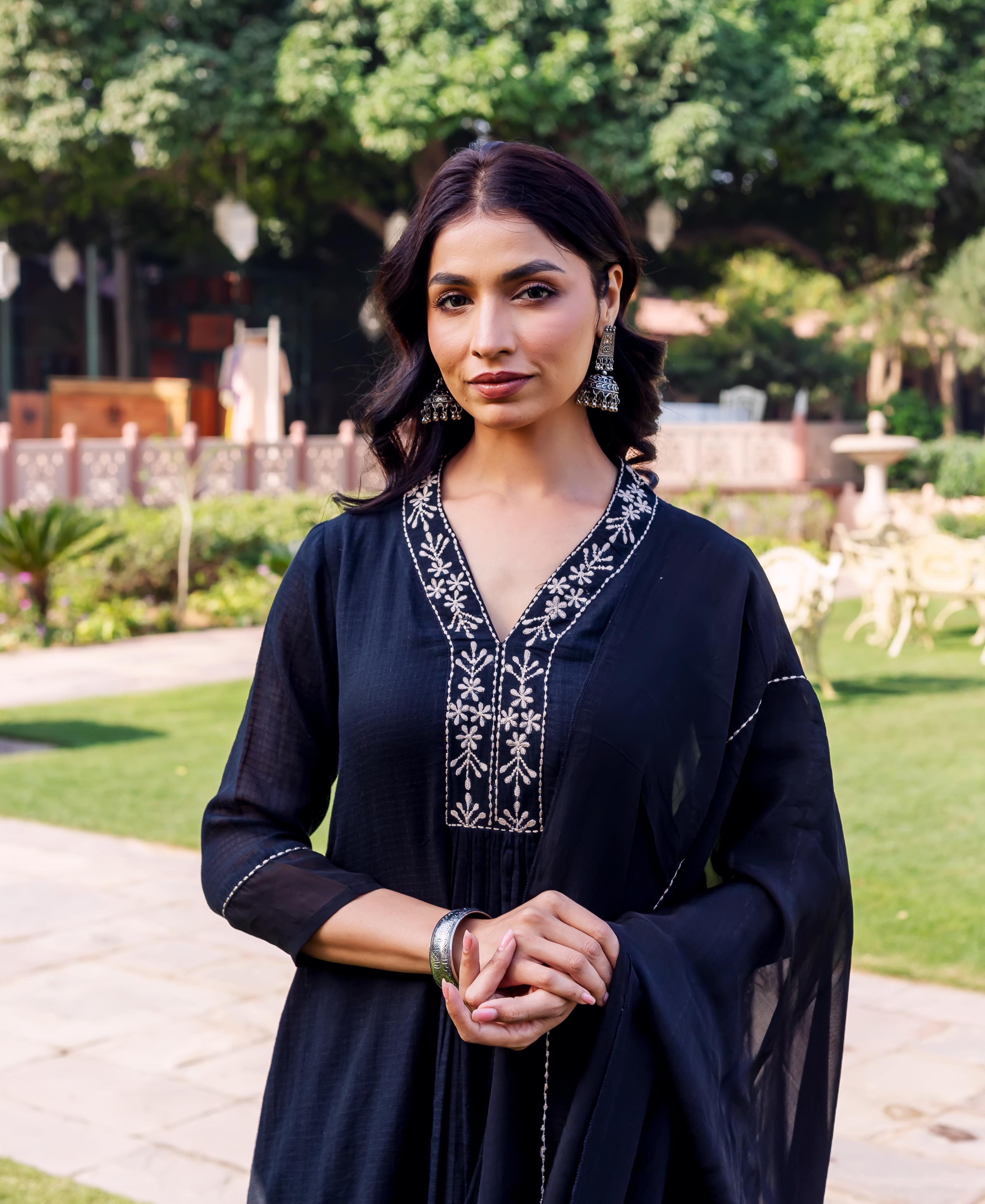 Front view of a woman in a black kurta with intricate white embroidered V-neck.