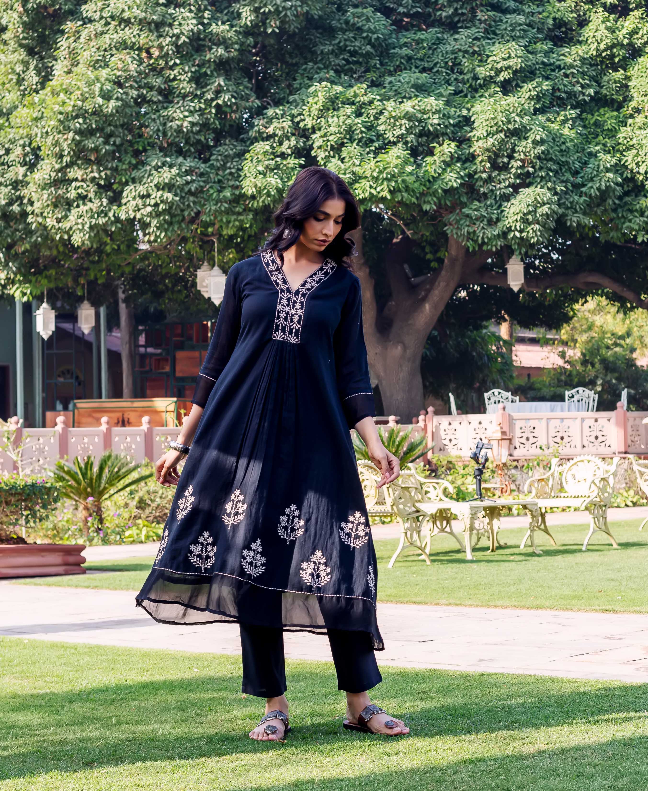 Full-length model in a dark blue ethnic kurta with white V-neck and hem prints.